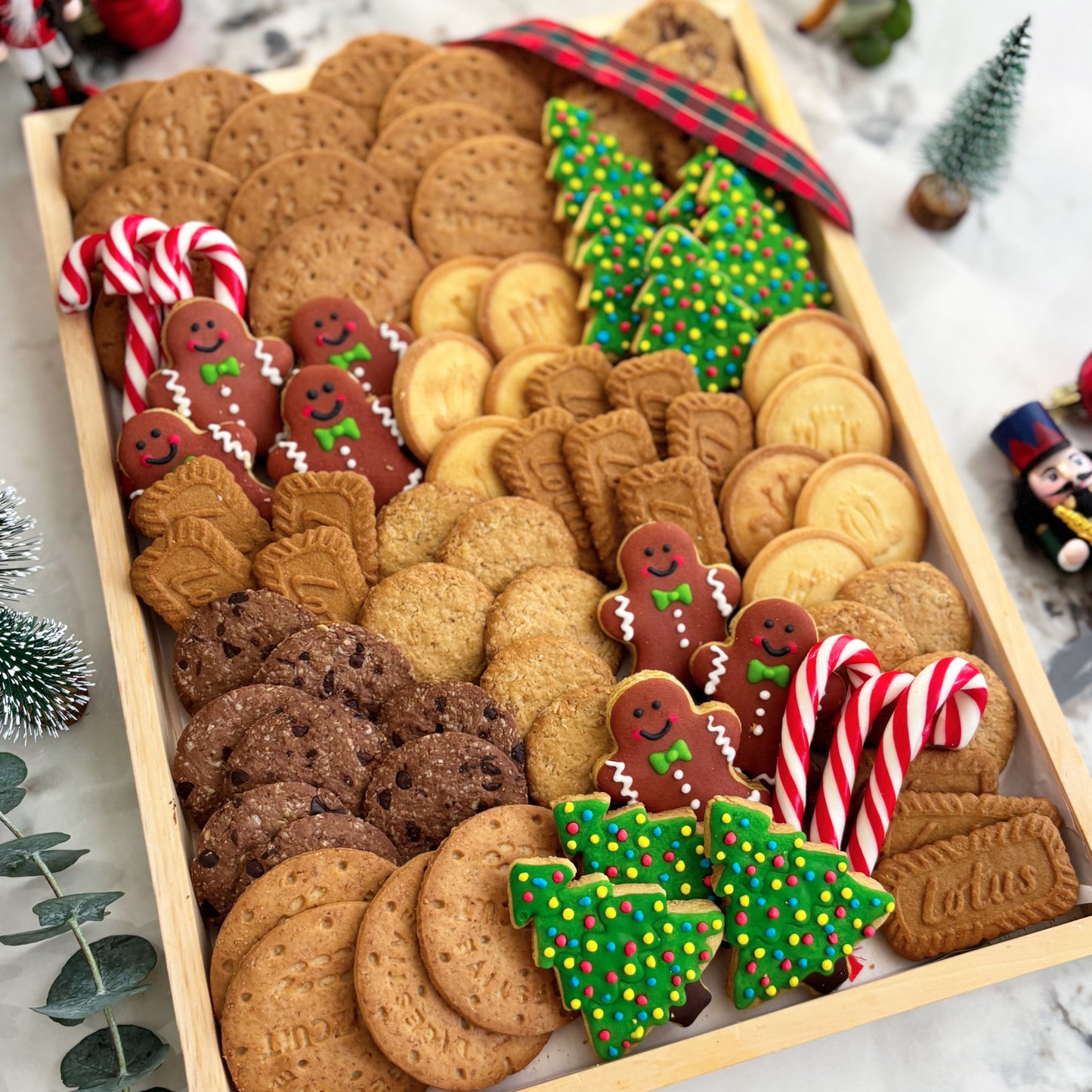 Assorted Christmas cookies including gingerbread men, trees, and candy canes on a wooden tray. Christmas platter, hamper natal jakarta, hamper natal surabaya. Celebrate Christmas with Le Bliss Platter’s Cookies Platter — festive cookies & treats beautifully arranged. Available for delivery in Jakarta & Surabaya.