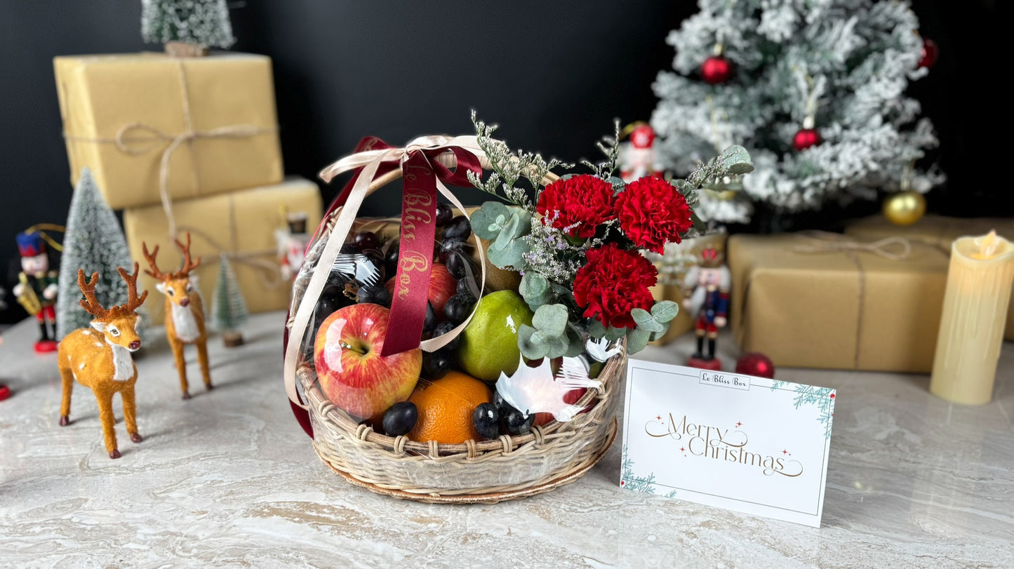 Festive gift basket with fruits, flowers, and a card on a decorative table with Christmas decorations. Christmas Blossom Fruit Parcel | Best Christmas Hamper Jakarta, Tangerang, Cirebon & Surabaya by le bliss box
