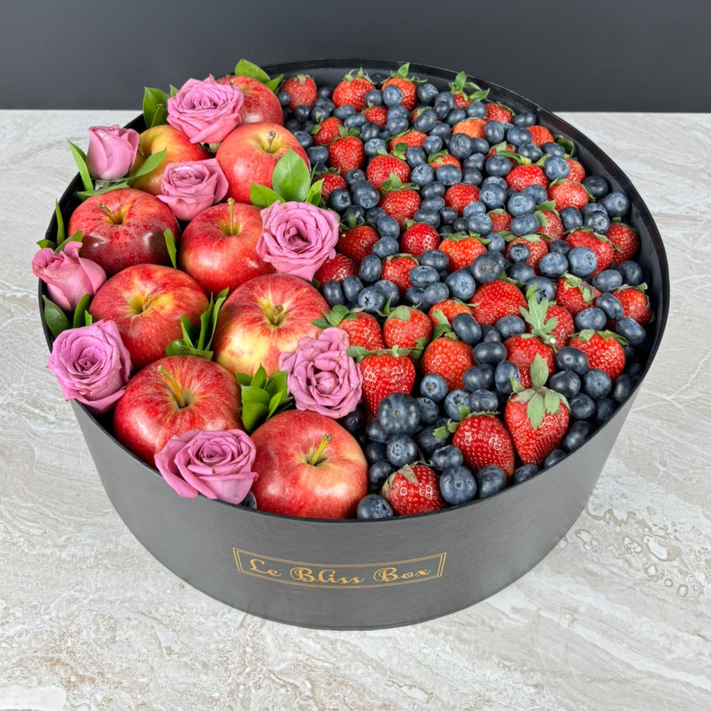 Fruit and flower arrangement in a black box with 'Le Bliss Box' branding. Decorative box filled with fruits and flowers, including apples, strawberries, and blueberries, with a 'Happy Mother's Day' card. kado hari ibu surabaya, jakarta, cirebon