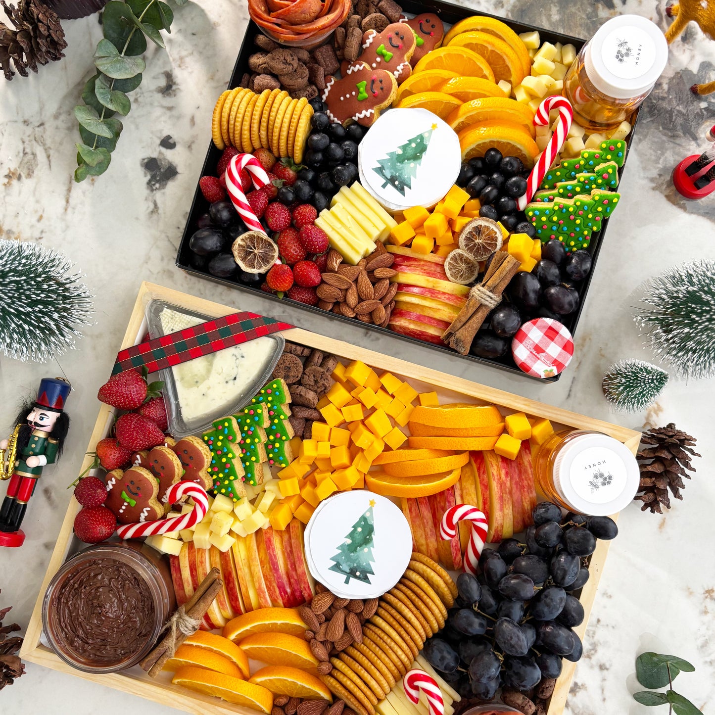 Holiday charcuterie board with fruits, cheeses, and nuts on a white surface with Christmas decorations. Christmas Xtra Cheese Platter | Best Cheese Platter in Jakarta & Surabaya – Le Bliss Platter