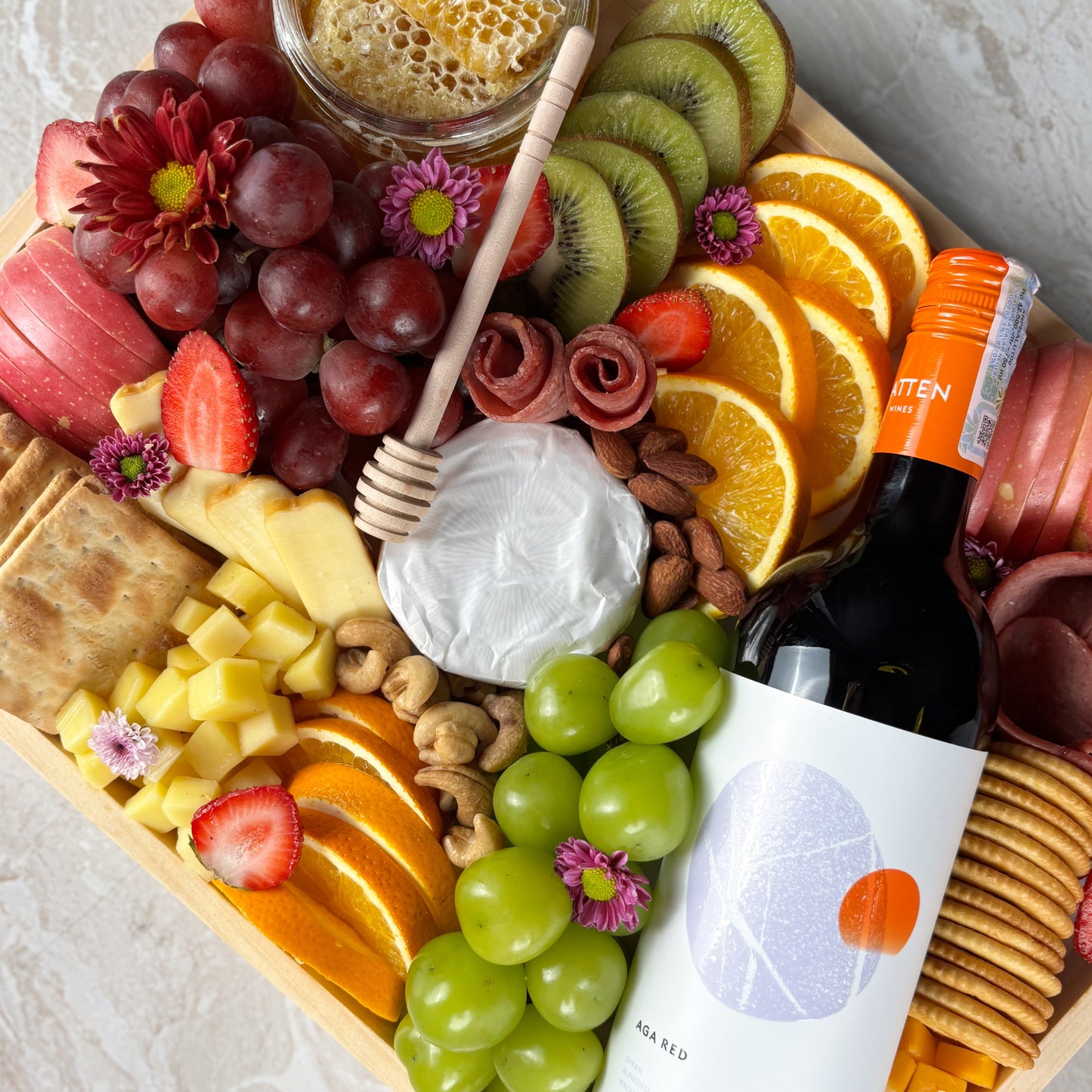 Red wine cheese platter on wooden tray with fruits and cheeses by le bliss platter. Luxury cheese platter gift with wine, grapes, and brie. best platter in jakarta, surabaya, cirebon