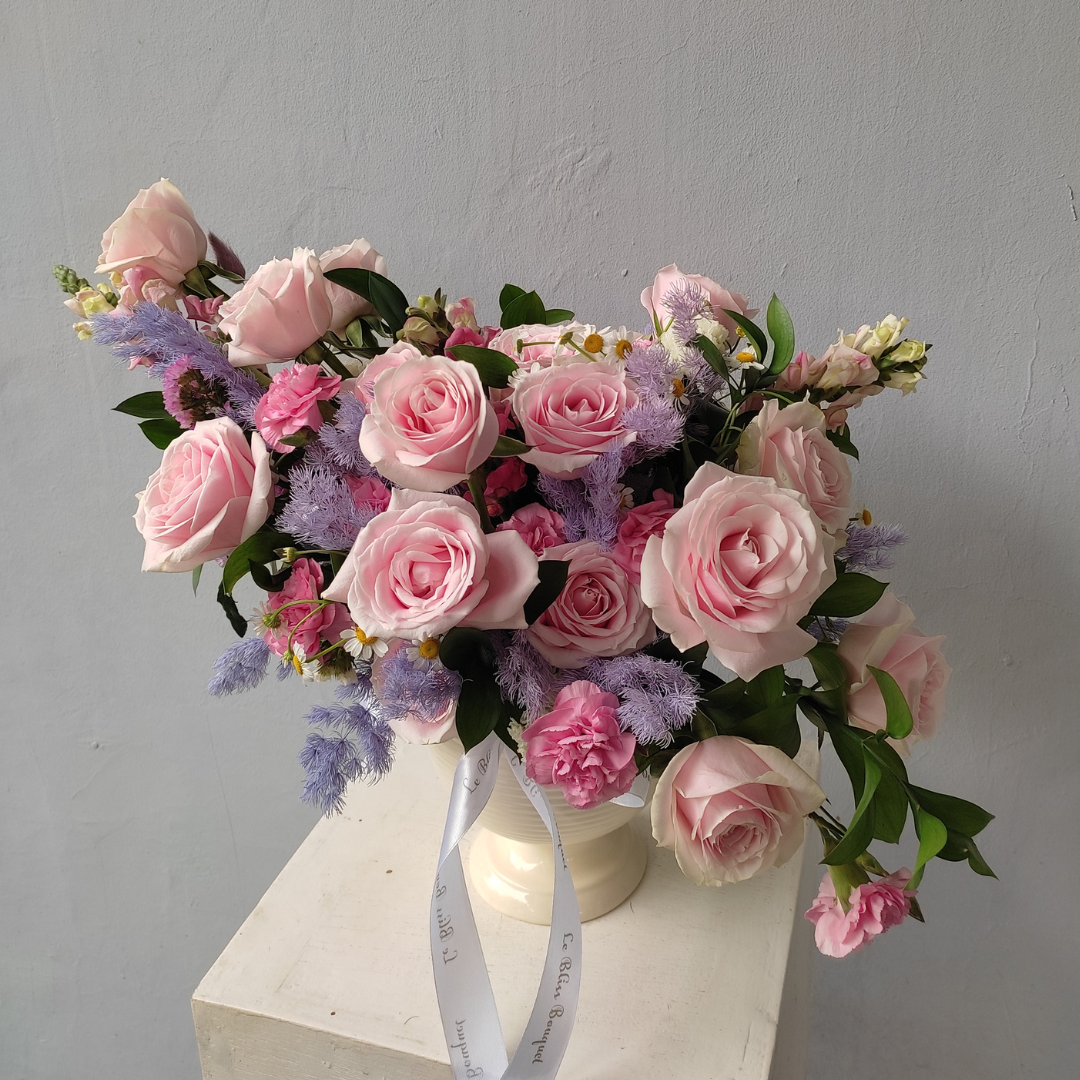 A floral arrangement featuring pink avalanche roses, gompie pink blooms, and lily casablanca in a white vase, set against a neutral background. florist surabaya, toko bunga surabaya, vase arrangement surabaya, sidoarjo, gresik
