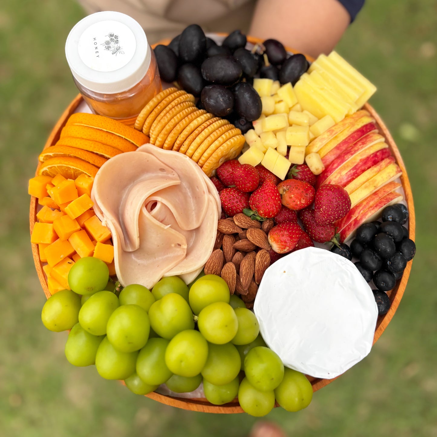 Assorted fruits, cheeses, and meats on a platter by le bliss platter. cheese platter jakarta, cheese platter surabaya, with chicken salami