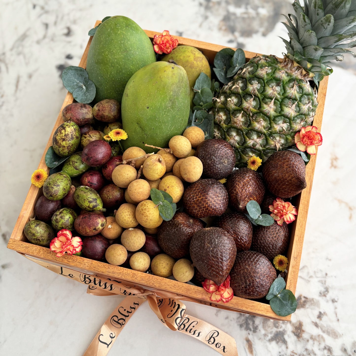 Assorted fruits in a wooden box with 'Le Bliss Box' branding on a marble surface. parcel buah surabaya, parcel buah jakarta. tropical fruits hamper jakarta, surabaya, cirebon