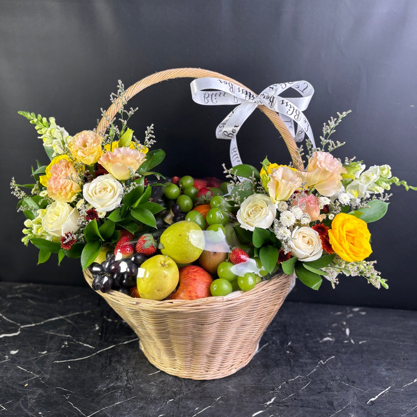 Basket of flowers and fruits with a black background. Royal harvest fruity parcel, parcel buah surabaya, parcel buah jakarta, parcel buah indonesia, fruit hamper delivery by le bliss box