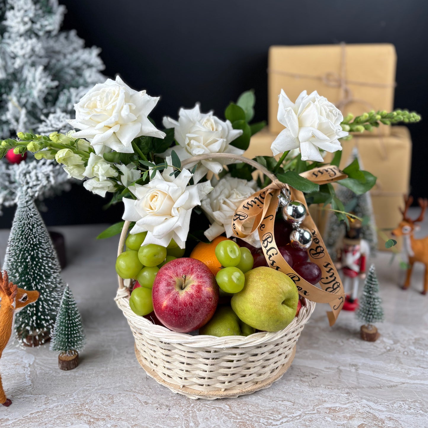 Basket of fruits and flowers with Christmas decorations in the background. Parcel buah natal cirebon, parcel buah surabaya. Blooming Winter Sonata Fruit Basket dari Le Bliss Box. Christmas fruit hamper mewah dengan buah premium & dekorasi festive. Pengiriman Surabaya, Jakarta & Cirebon.