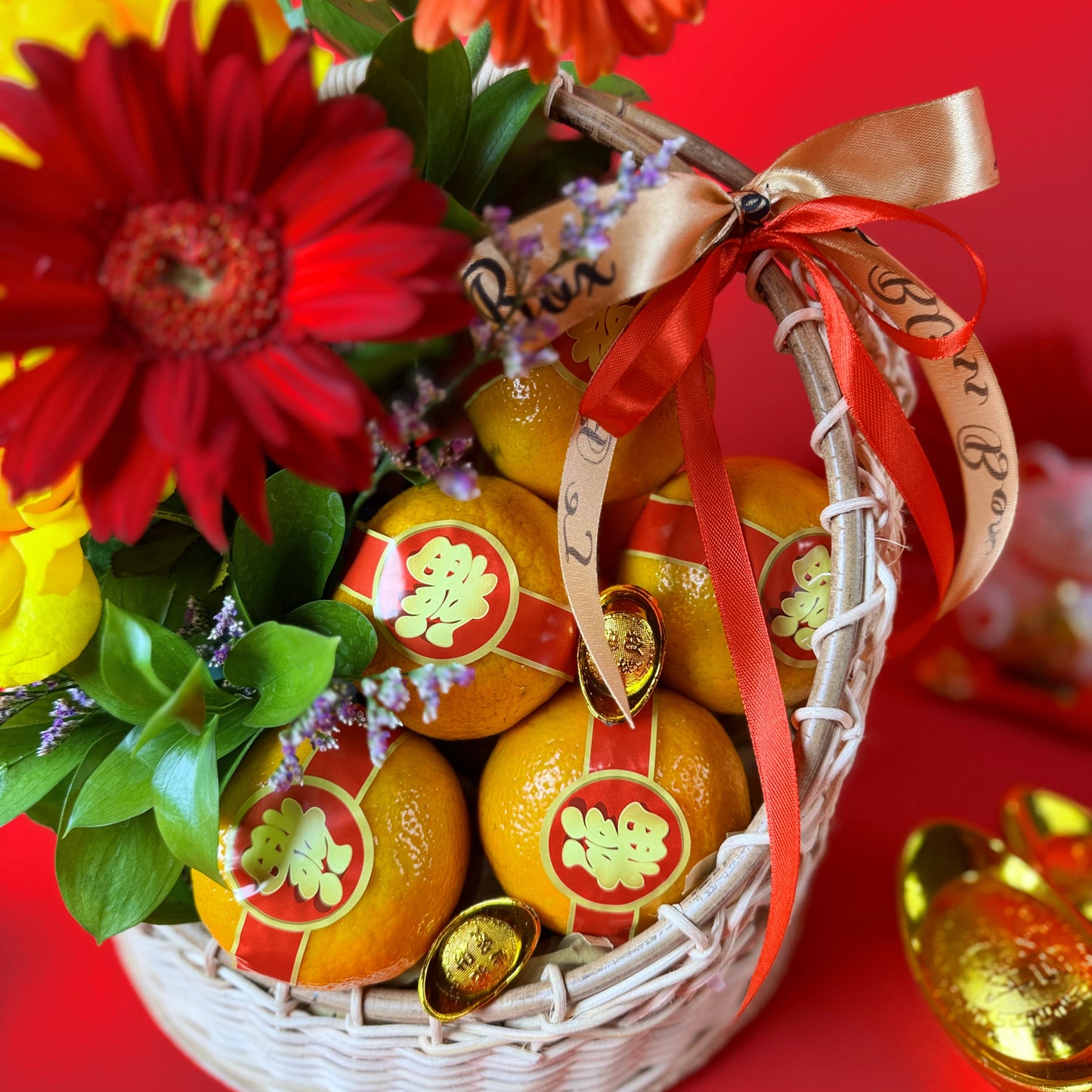 Basket of oranges with red ribbons and flowers on a red background