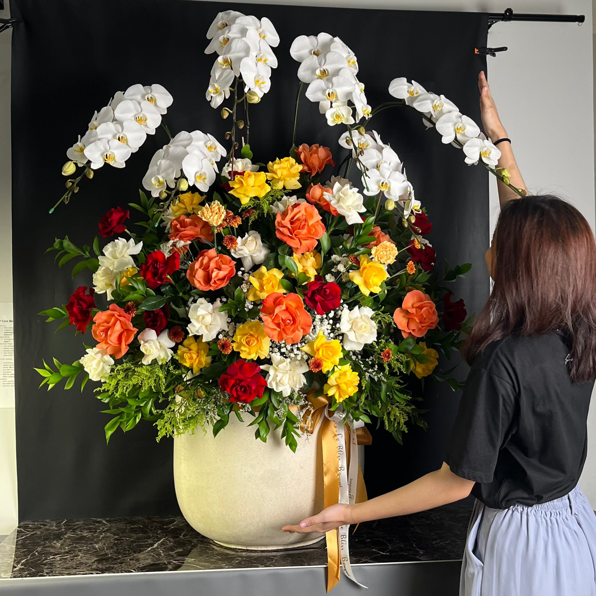 Big Vase arrangement by Le Bliss boUQUET. Florist jakarta, florist surabaya, florist cirebon. Person arranging flowers in a vase with a black backdrop