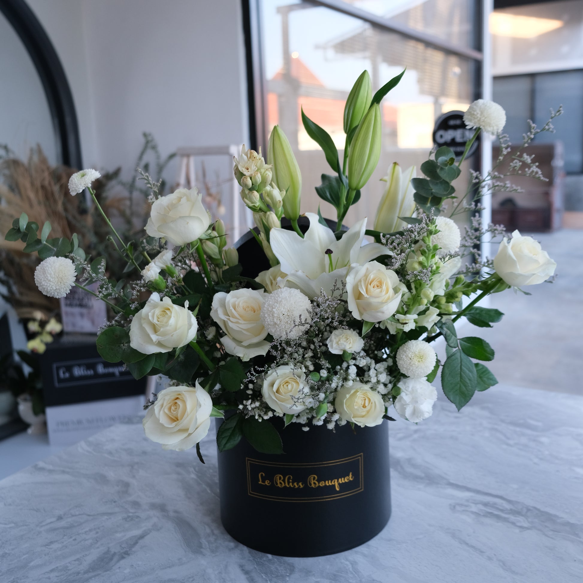 Bloombox elegan dengan lily putih dan mawar putih dari florist Surabaya, cocok untuk hadiah spesial dan pengiriman ke Cirebon & Jabodetabek. florist surabaya
