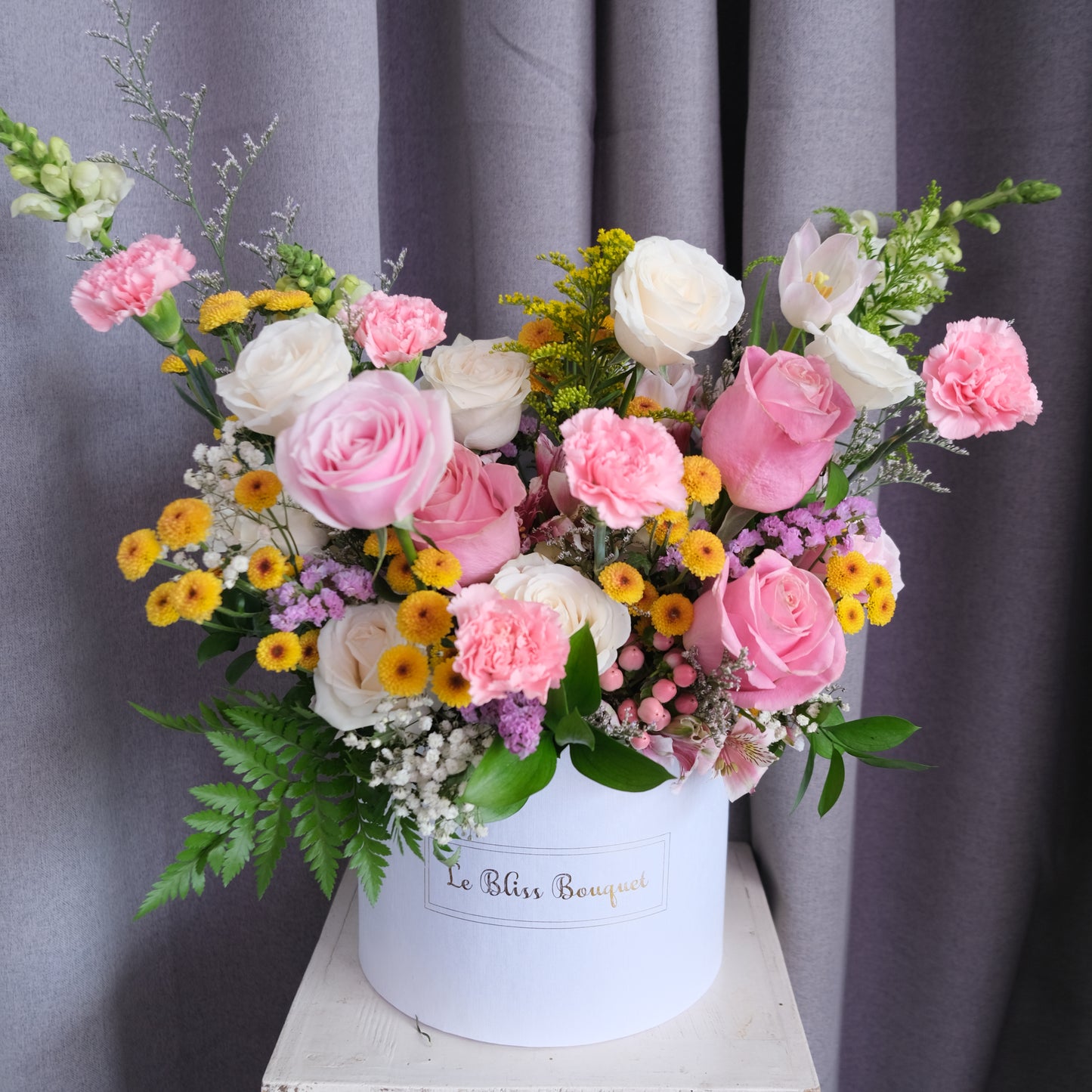 Bloombox flowers with a white cylindrical container on a gray background. Jakarta florist, tangerang, surabaya, cirebon. toko bunga jakarta