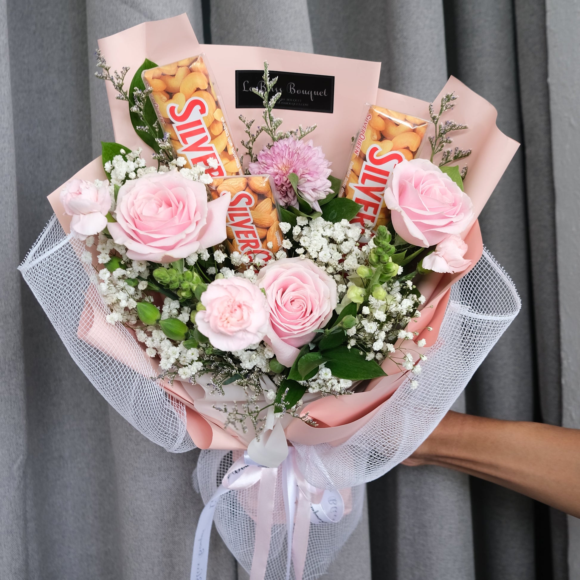 Bouquet of flowers with silverqueen chocolate bars wrapped in paper against a gray background