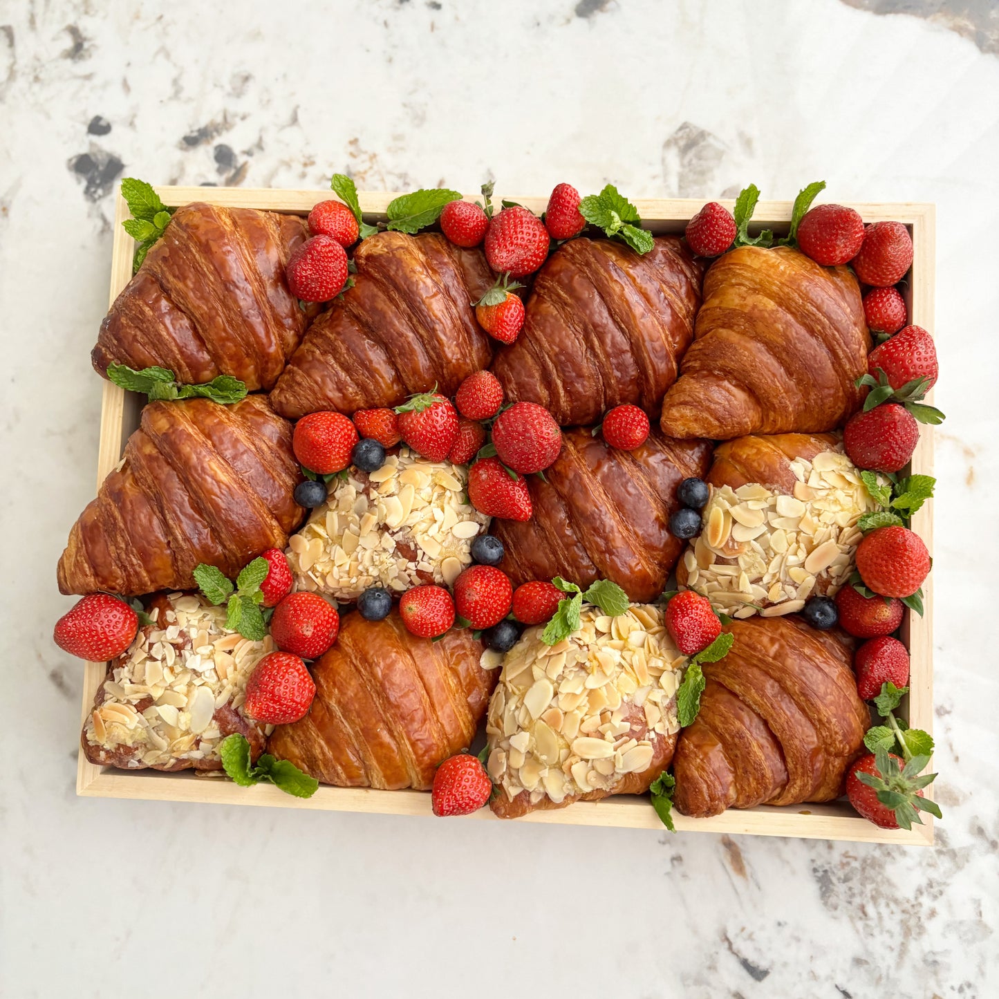 Box of croissants and pastries with berries on a marble surface. best platter in jakarta, best platter in surabaya. by le bliss platter