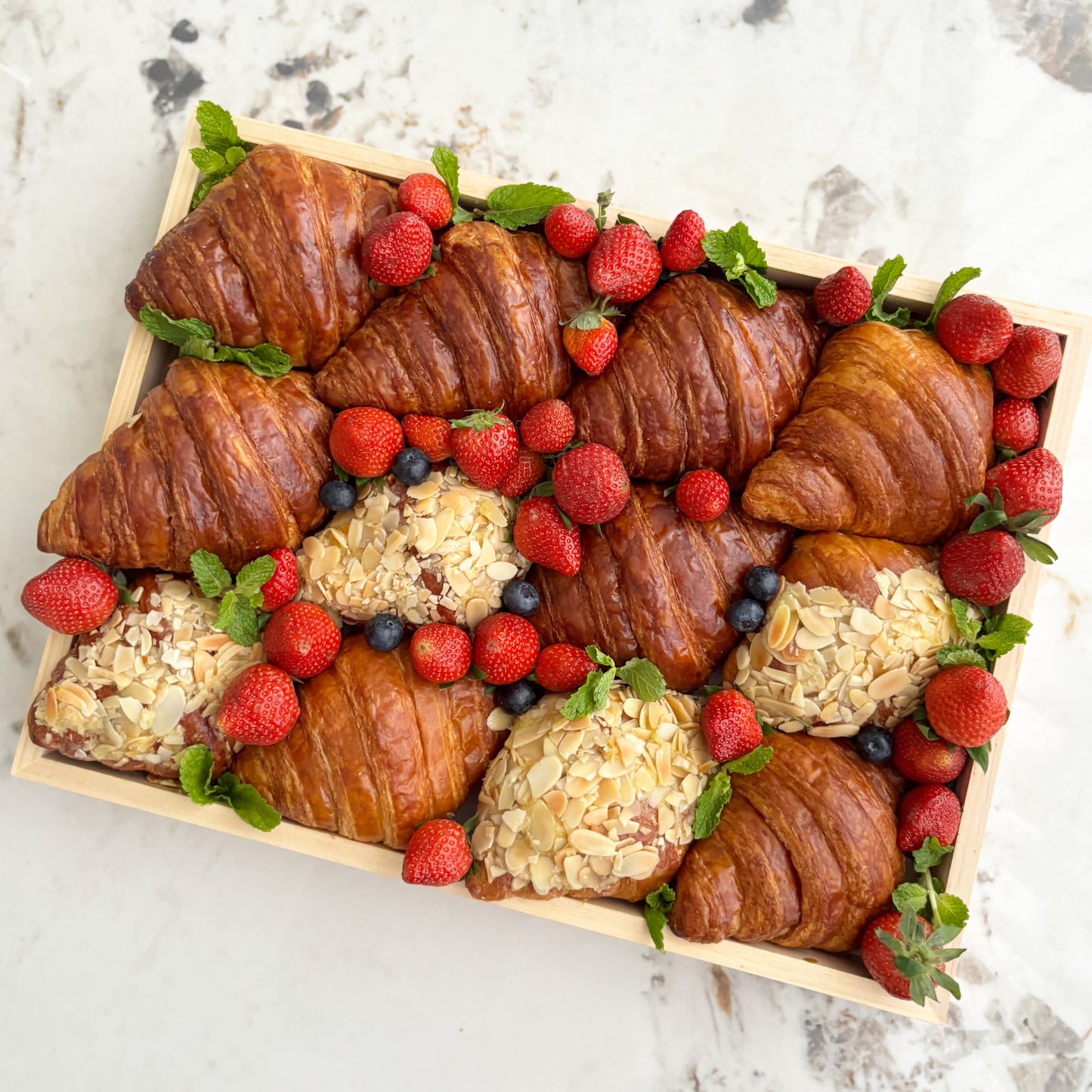 Box of croissants and pastries with berries on a marble surface. best platter in jakarta, best platter in surabaya