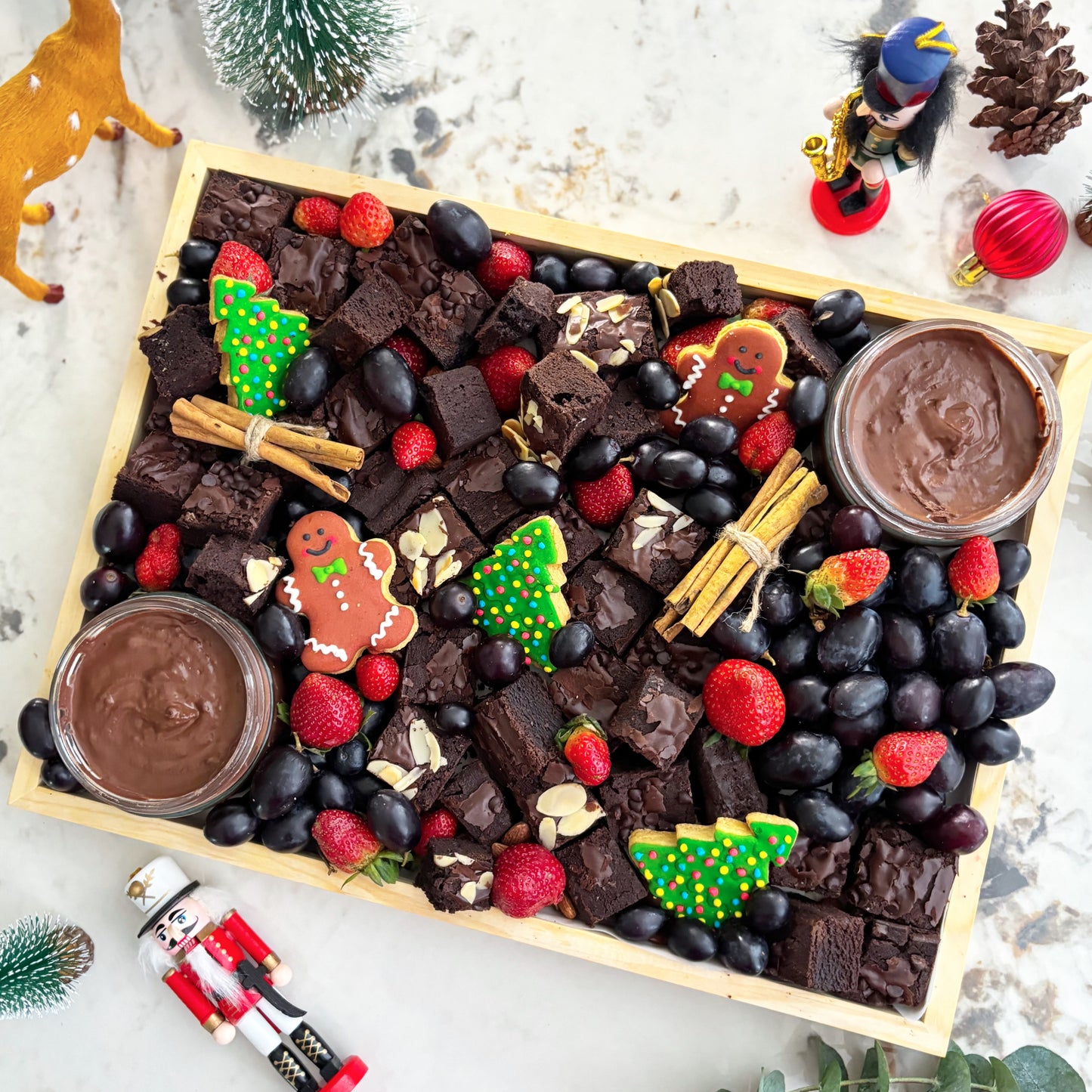 Chocolate brownie platter with berries, cookies, and dips on a wooden board with Christmas decorations. Xtra Christmas Brownies Platter | Christmas Platter Jakarta & Surabaya – Le Bliss Platter