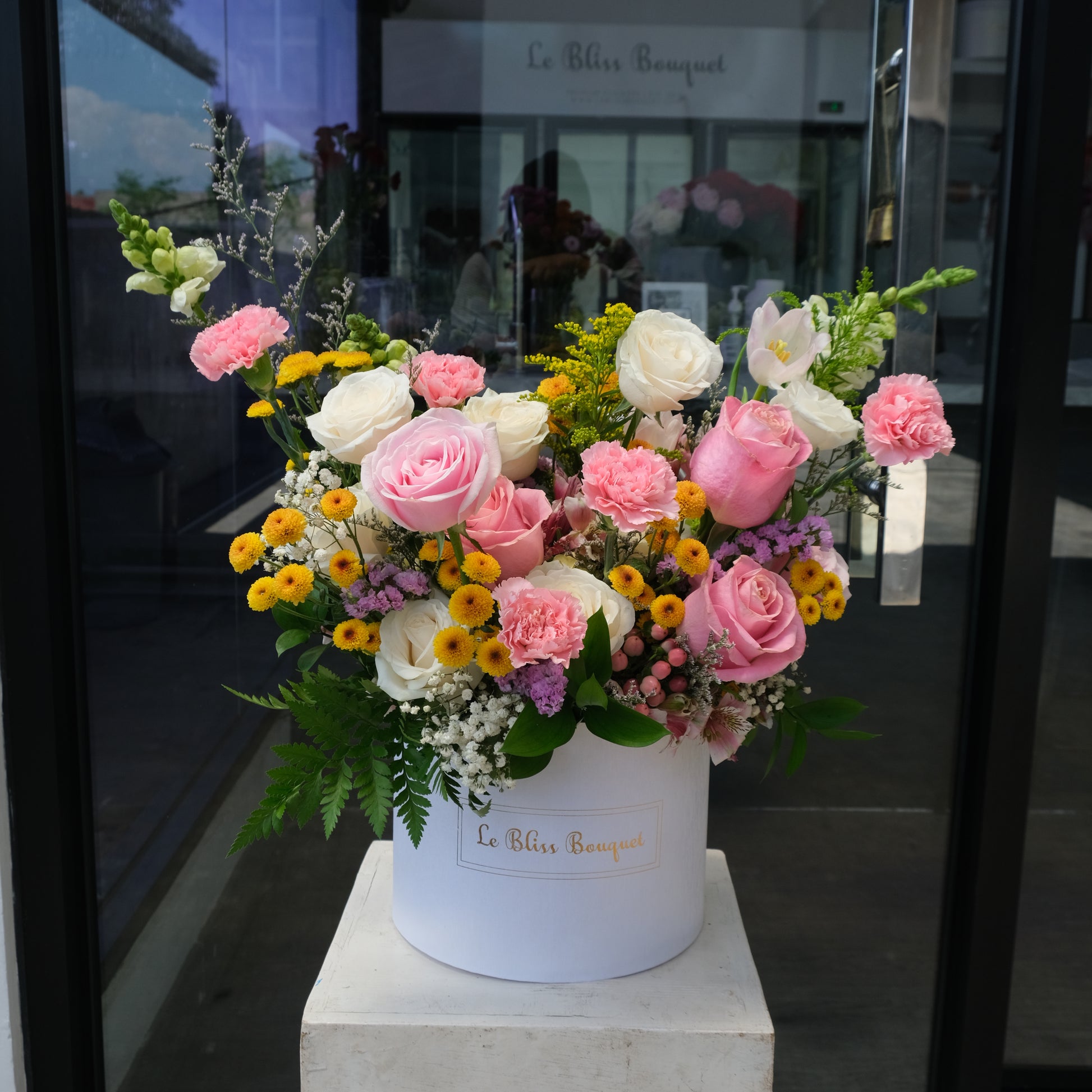 Colorful flower arrangement in a white box with 'Le Bliss Bouquet' branding. Bloombox flowers with a white cylindrical container on a gray background. Jakarta florist, tangerang, surabaya, cirebon. toko bunga jakarta