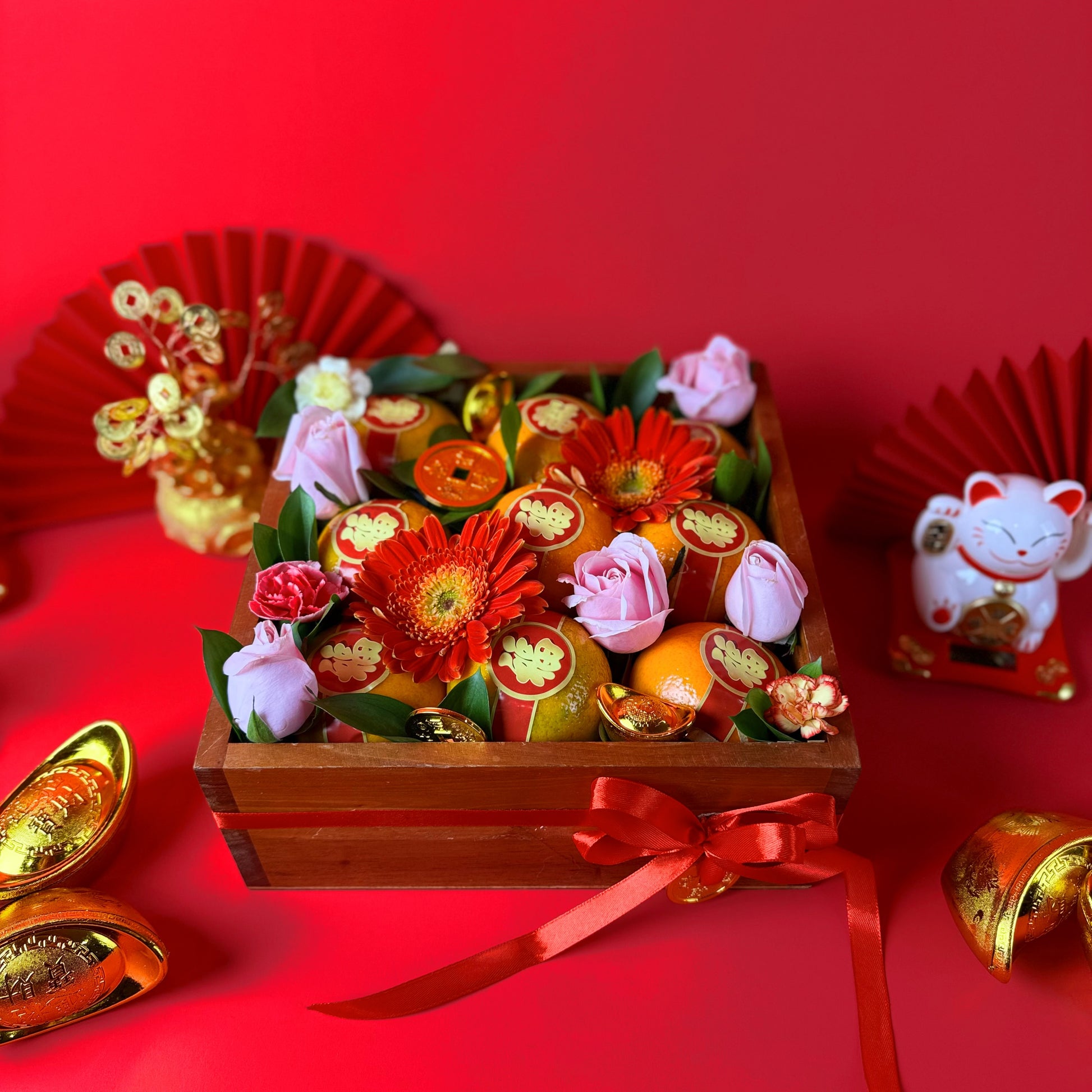 Decorative arrangement of flowers and fruits in a wooden box with a red ribbon on a red background. CNY Orange Wooden Box hamper – Chinese New Year gift hamper for Jakarta Tangerang Cirebon Surabaya