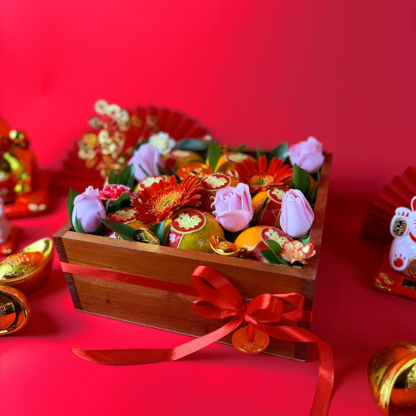 Decorative flower arrangement in a wooden box with a red ribbon on a red background. 