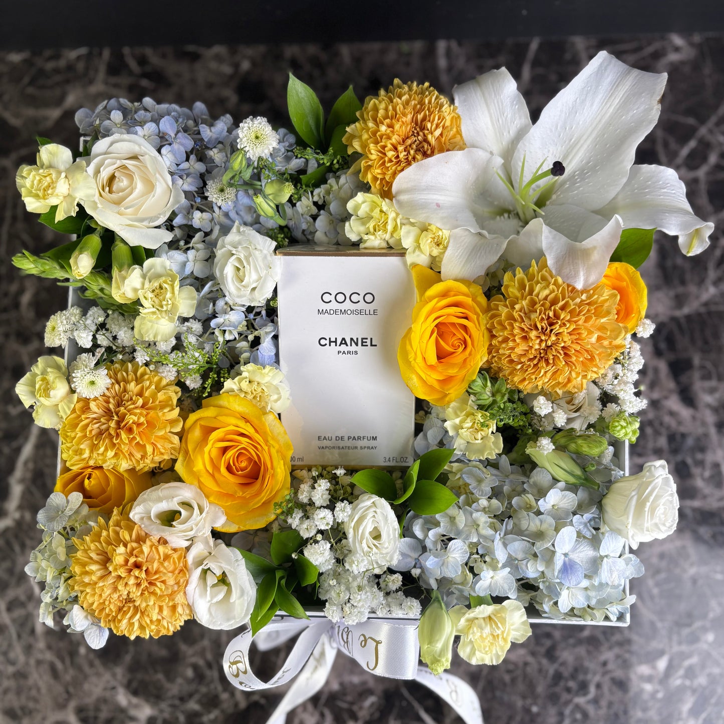 Floral arrangement with a Chanel perfume bottle at the center on a marble surface. Perfume hamper jakarta, surabaya by le bliss bouquet