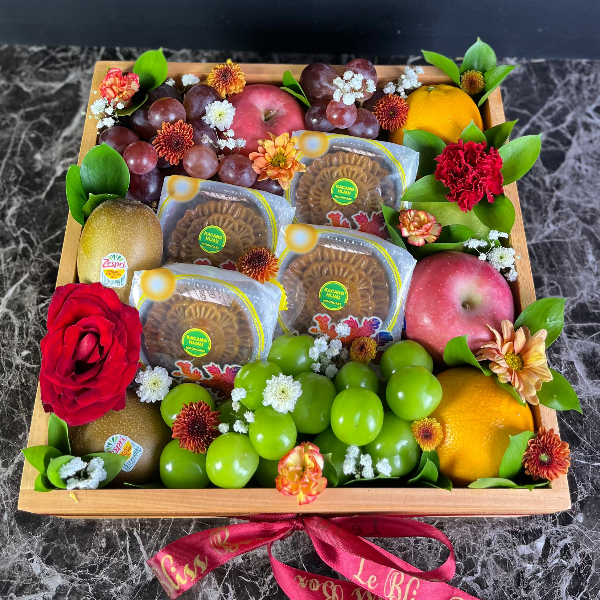 Fruit and cheese platter with flowers on a dark surface. Mooncake fruit hamper by le bliss. delivery to jakarta, surabaya, tangerang, jabodetabek