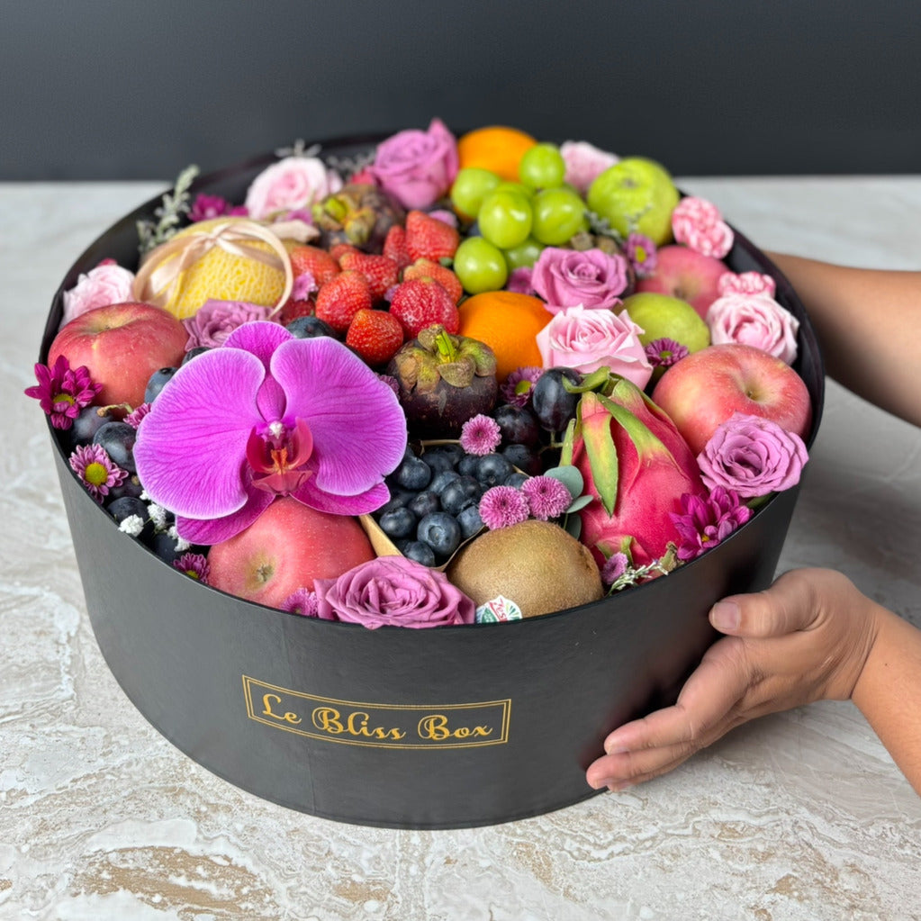 Fruit and flower arrangement in a black box held by a person, with 'Le Bliss Box' branding. Parcel Buah Surabaya, Jakarta, Cirebon