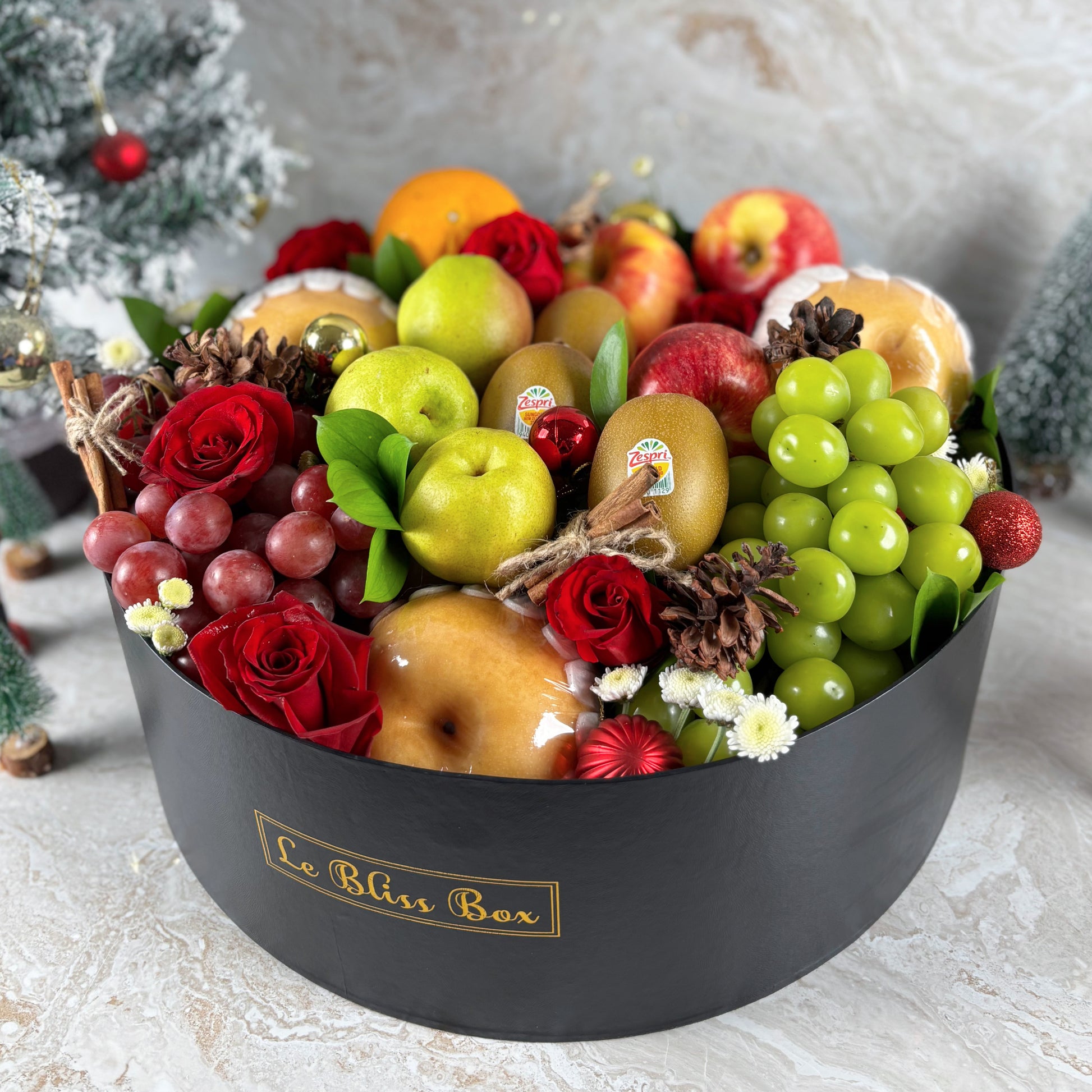 Fruit and flower arrangement in a black box labeled 'Le Bliss Box' on a light background. PARCEL BUAH NATAL, HAMPER NATAL JAKARTA, HAMPER NATAL SURABAYA