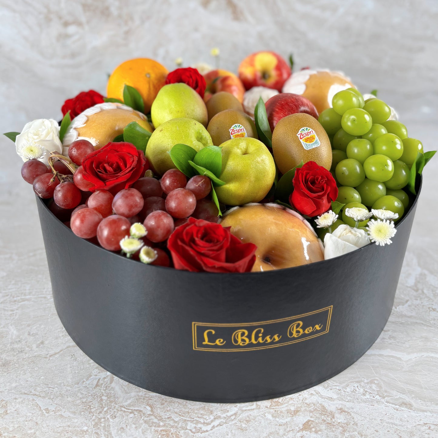 Fruit and flower arrangement in a black box labeled 'Le Bliss Box' on a light background. Parcel buah surabaya, parcel buah jakarta
