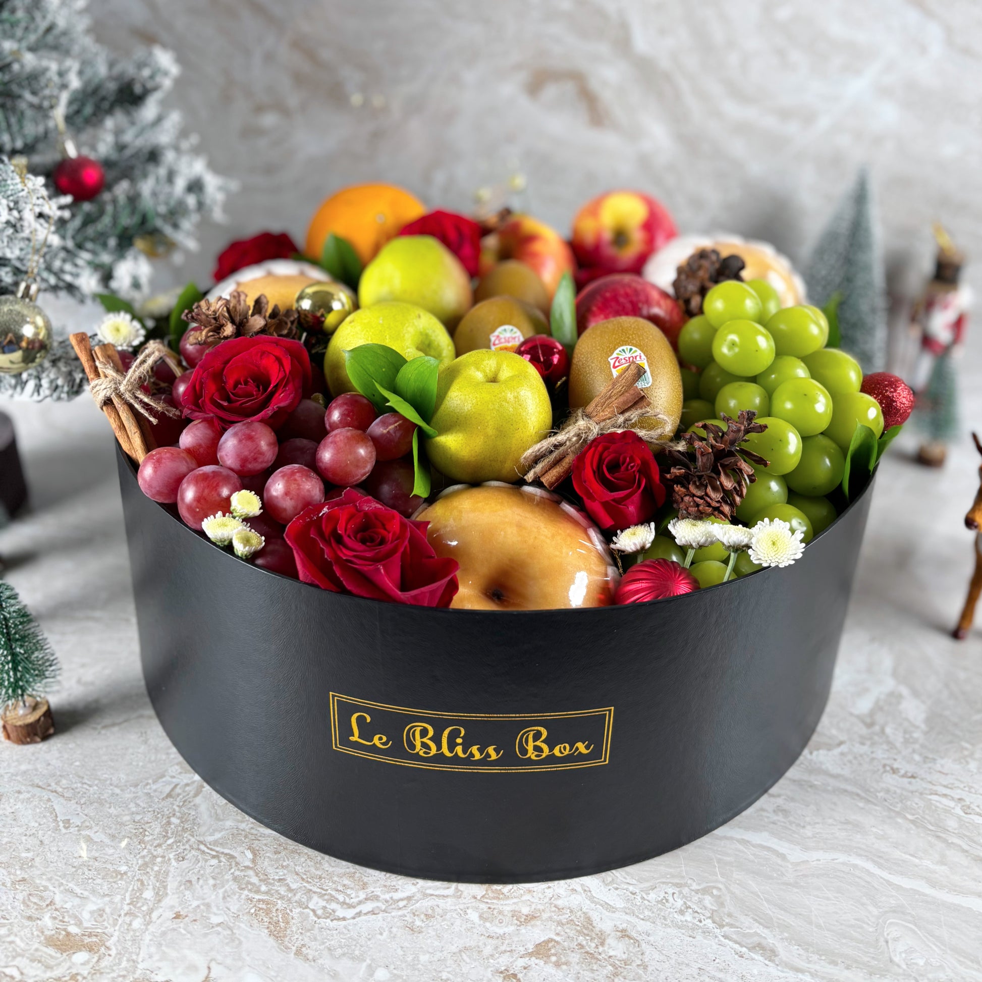 Fruit and flower arrangement in a black box labeled 'Le Bliss Box' on a light background. parcel buah natal, christmas hamper surabaya, christmas hamper jakarta