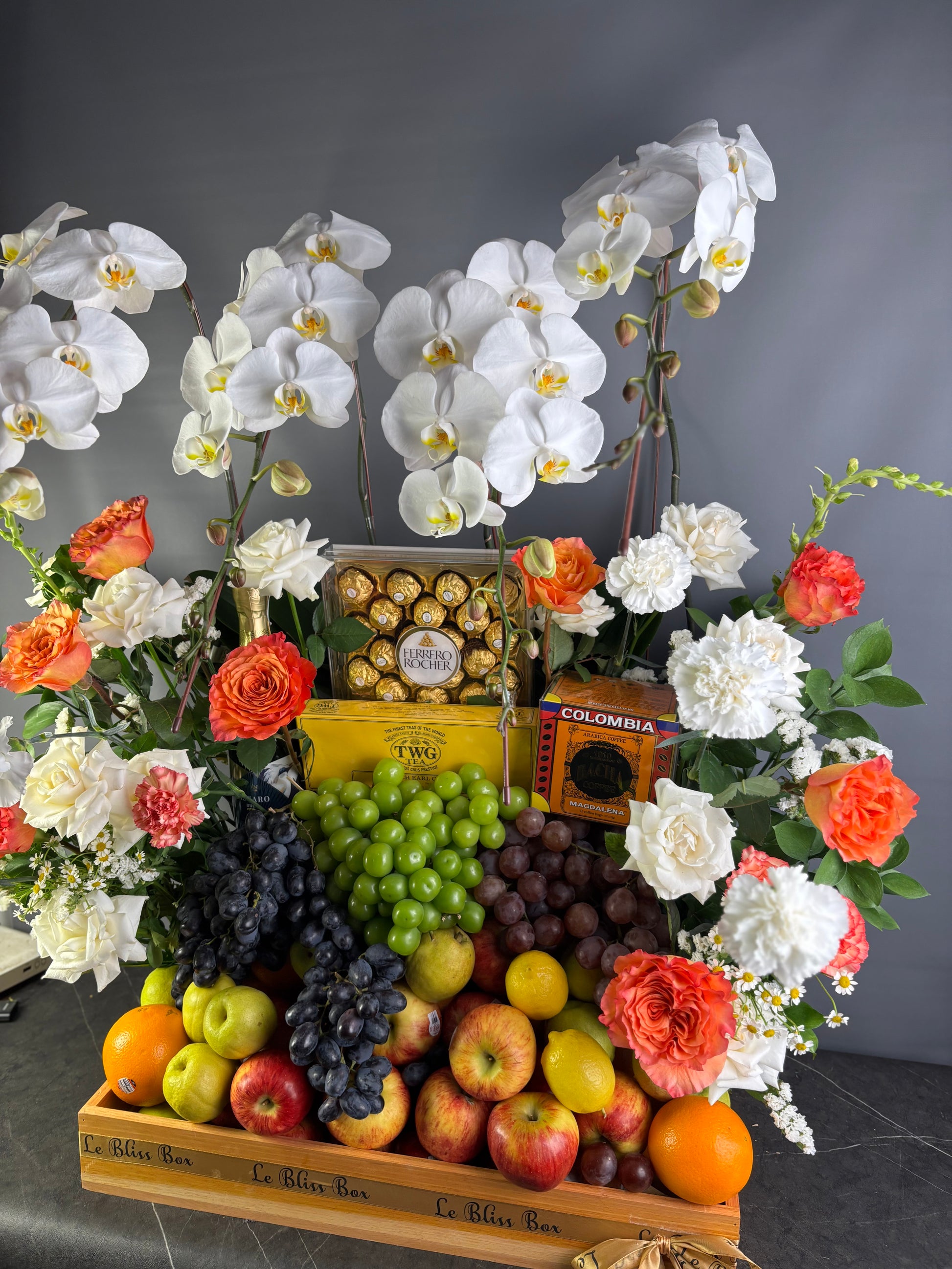 Fruit and flower arrangement with chocolates on a dark surface, wine hamper jakarta