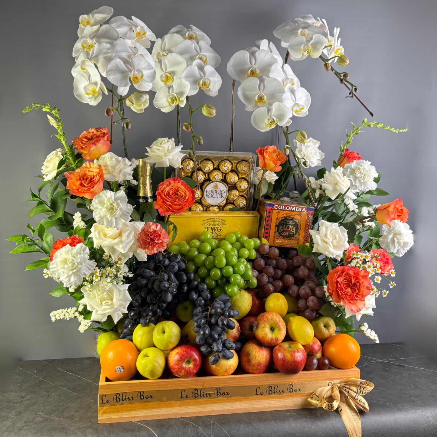 Fruit and flower arrangement with chocolates on a wooden stand against a gray background. luxury fruit hamper jakarta with wine. wine hamper surabaya & jakarta