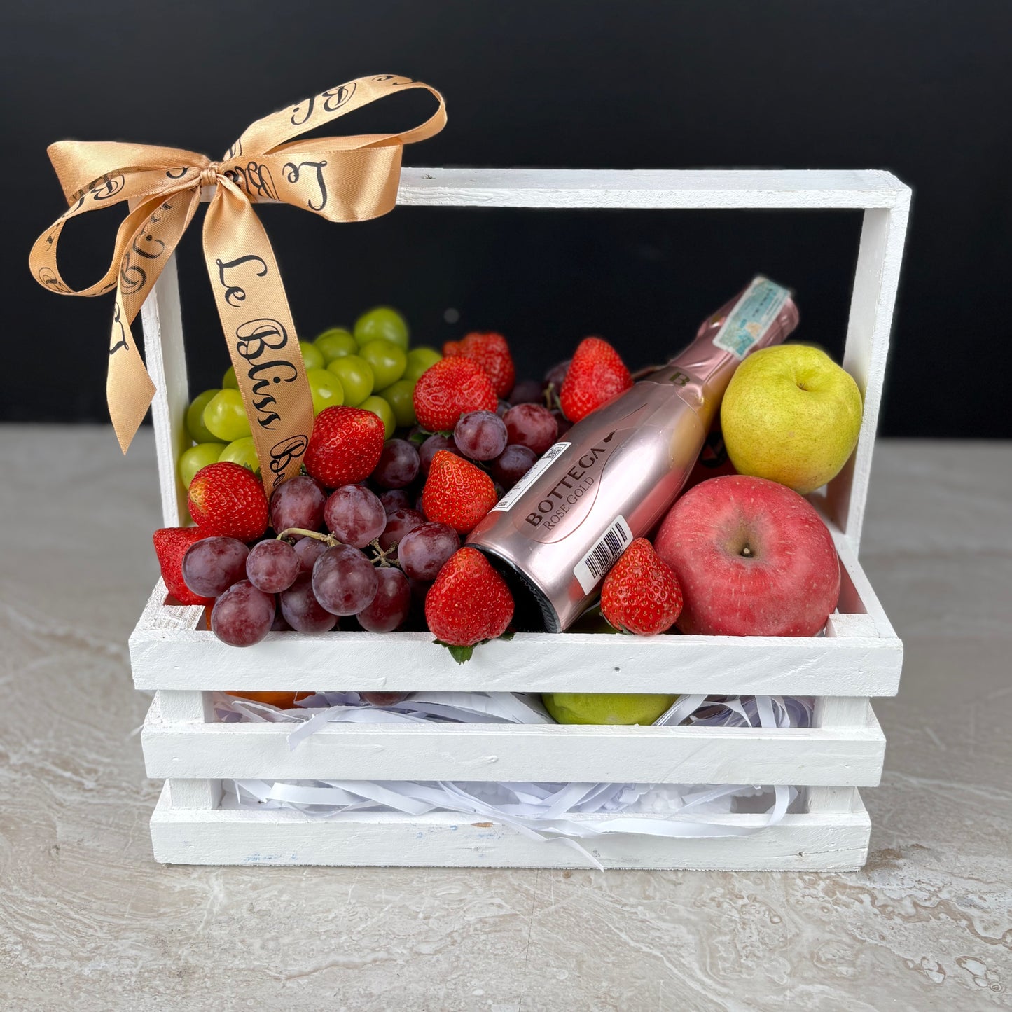 Fruit basket with a bottle of wine, grapes, strawberries, and apples on a white background. Fruit hamper with wine bottega jakarta, surabaya, cirebon