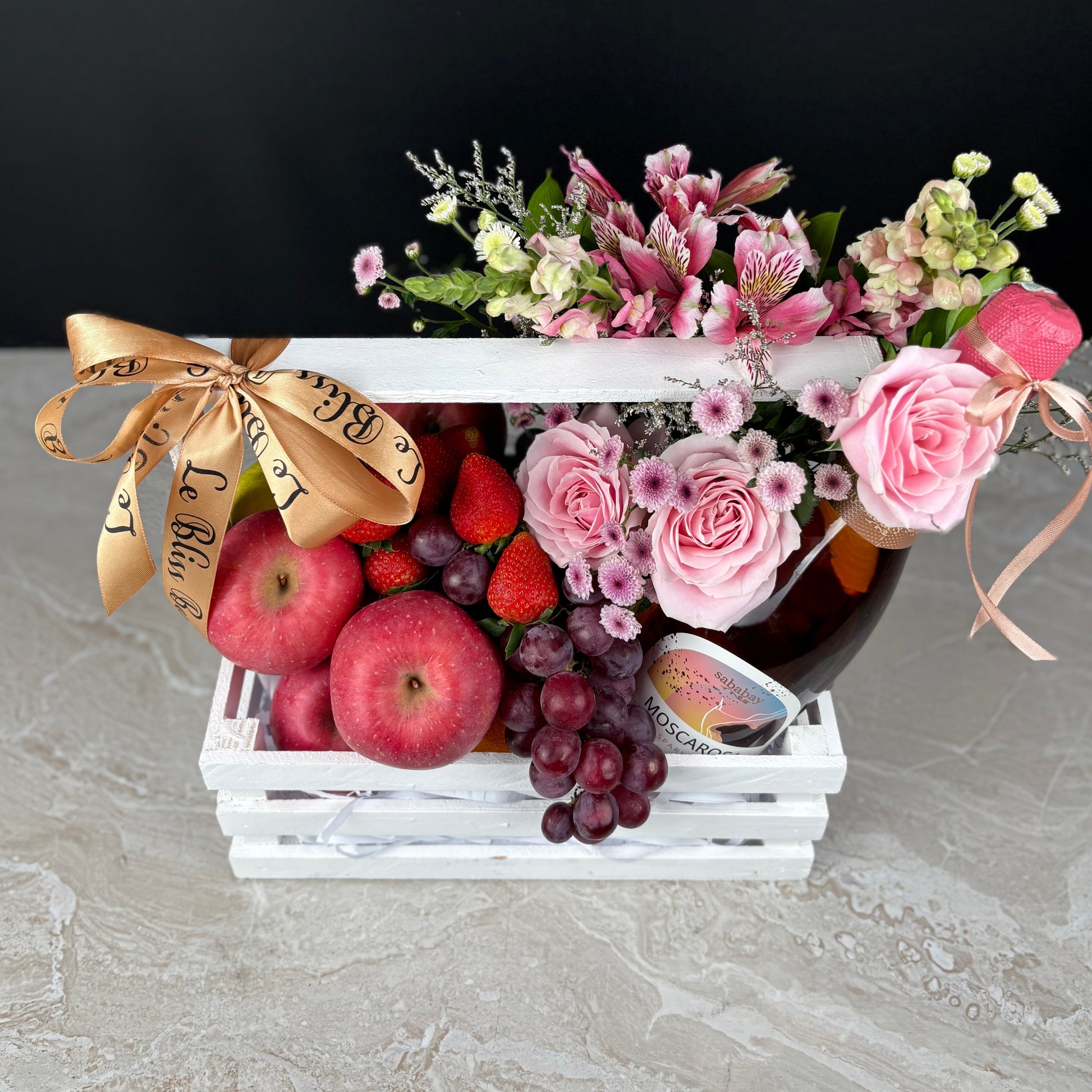 Fruit basket with apples, grapes, strawberries, and flowers in a white box on a gray surface. parcel buah wine surabaya, parcel buah jakarta, parcel buah tangerang