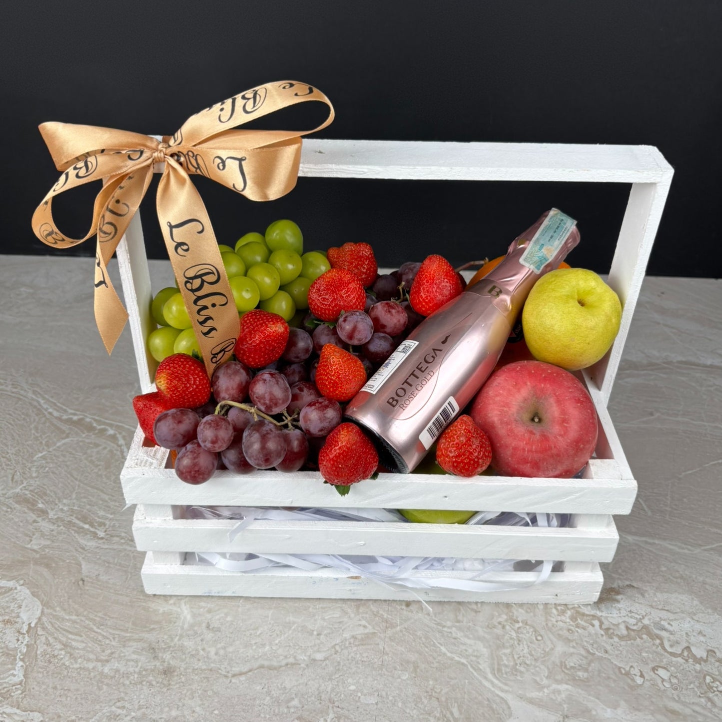 Fruit basket with grapes, strawberries, apples, and a bottle of Bottega on a white background. parcel buah surabaya, parceel buah wine jakarta. bottega wine hamper