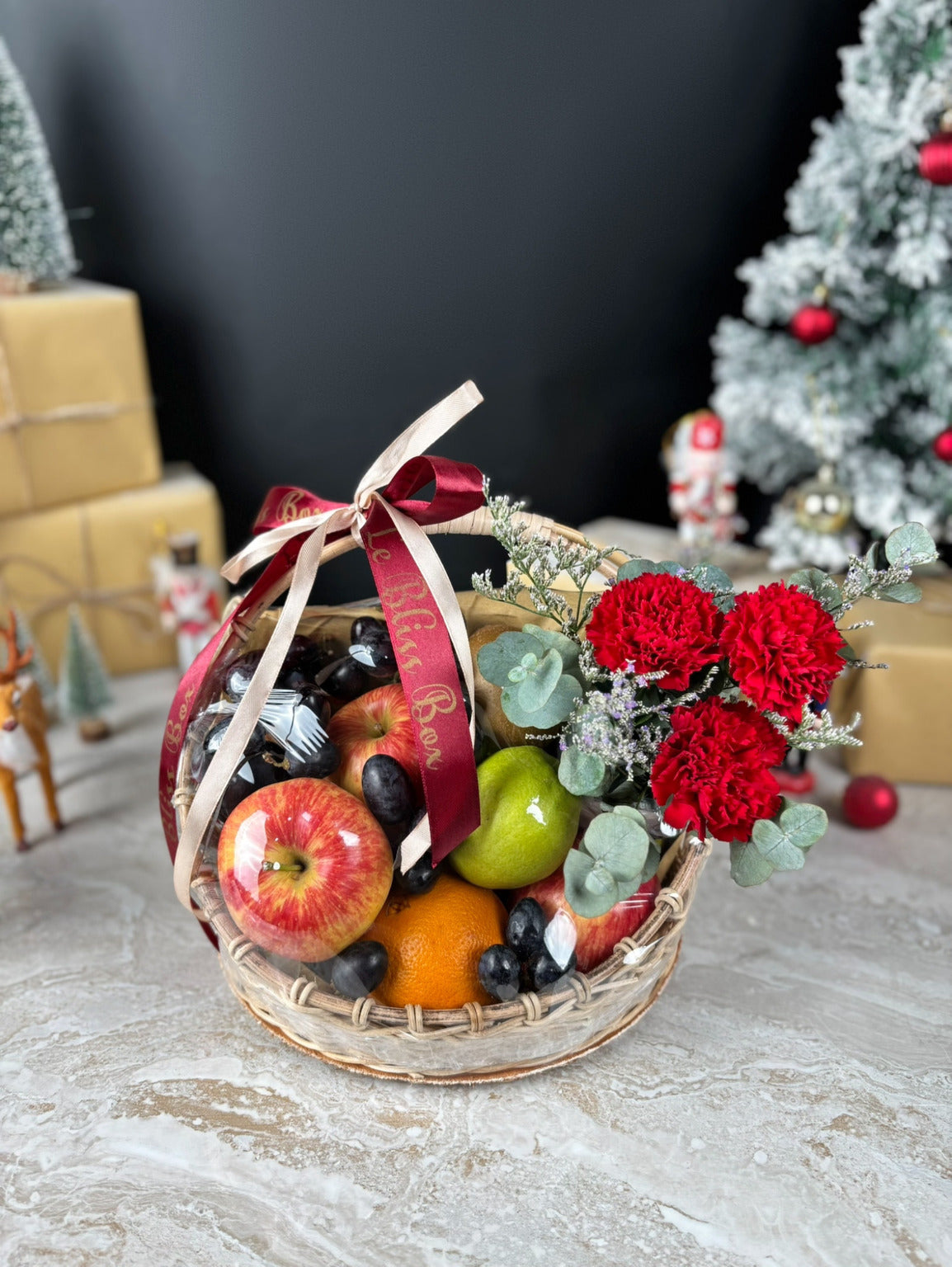 Fruit basket with red flowers and a decorative ribbon on a festive background. Christmas Blossom Fruit Parcel | Best Christmas Hamper Jakarta, Tangerang, Cirebon & Surabaya by le bliss