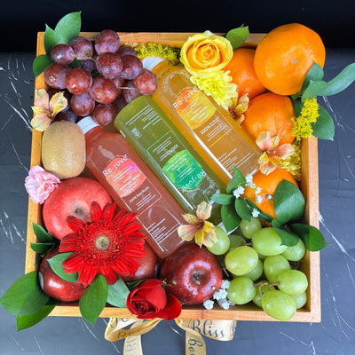 A wooden fruit box containing an assortment of fresh fruits such as apples, oranges, grapes, and bananas, along with two bottles of juice and decorative flowers. rejuve juice fruit hamper jakarta, surabaya, cirebon. parcel buah dengan juice rejuve