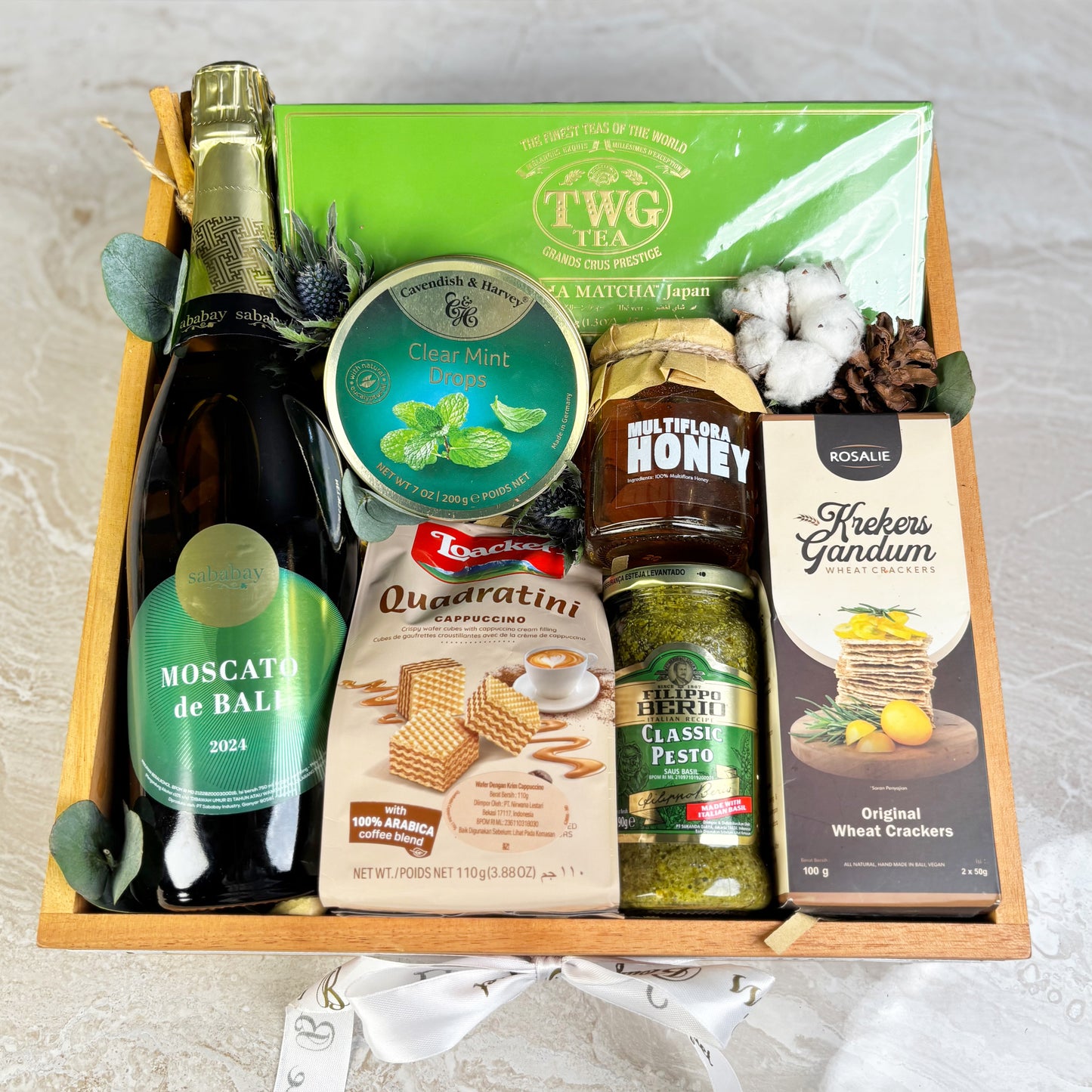 Gift basket with Moscato de Bali, TWG tea, honey, and other items on a light background. Premium parcel wine jakarta, parcel wine surabaya