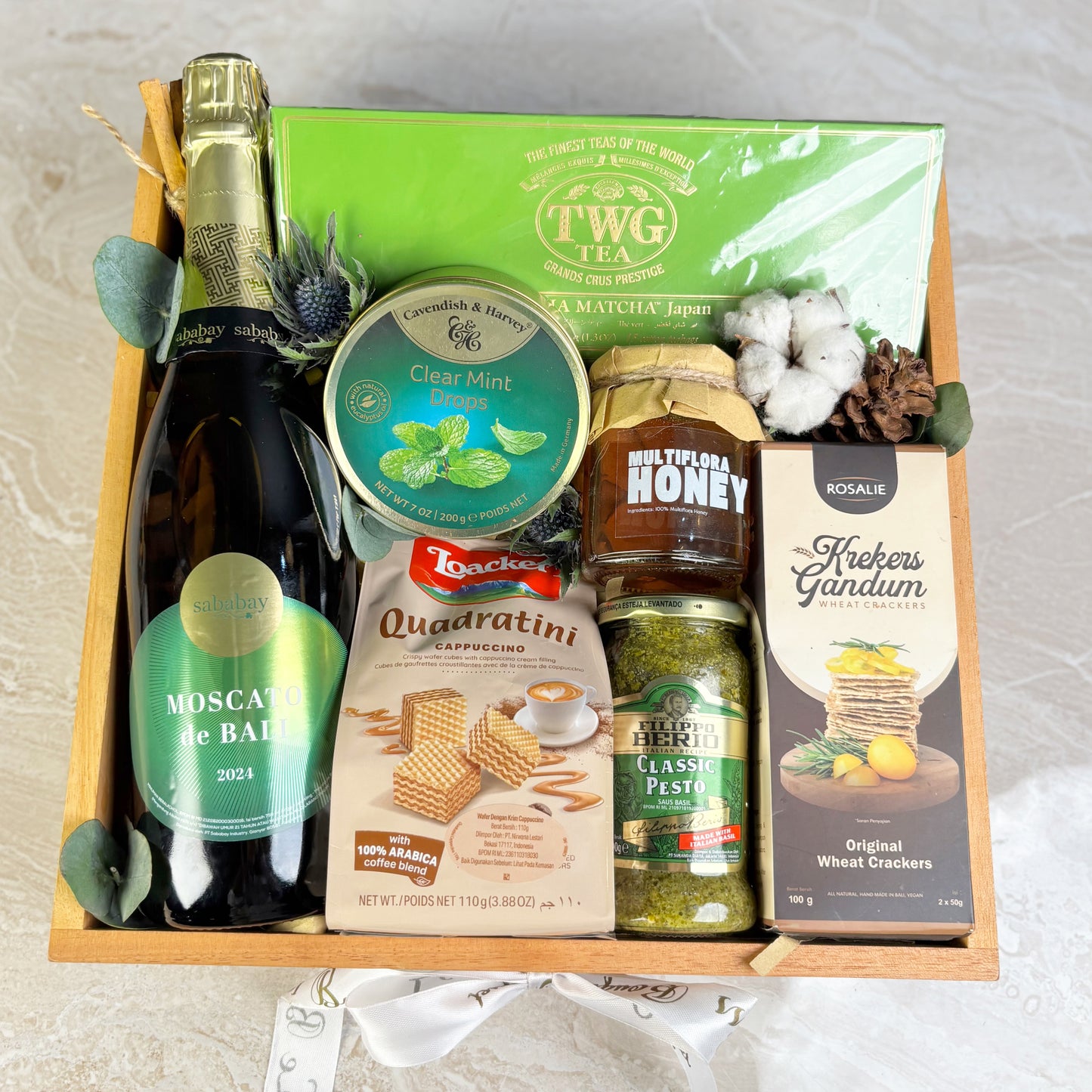 Gift basket with Moscato wine, tea, honey, and other snacks on a light background. Parcel wine premium surabaya, jakarta, tangerang