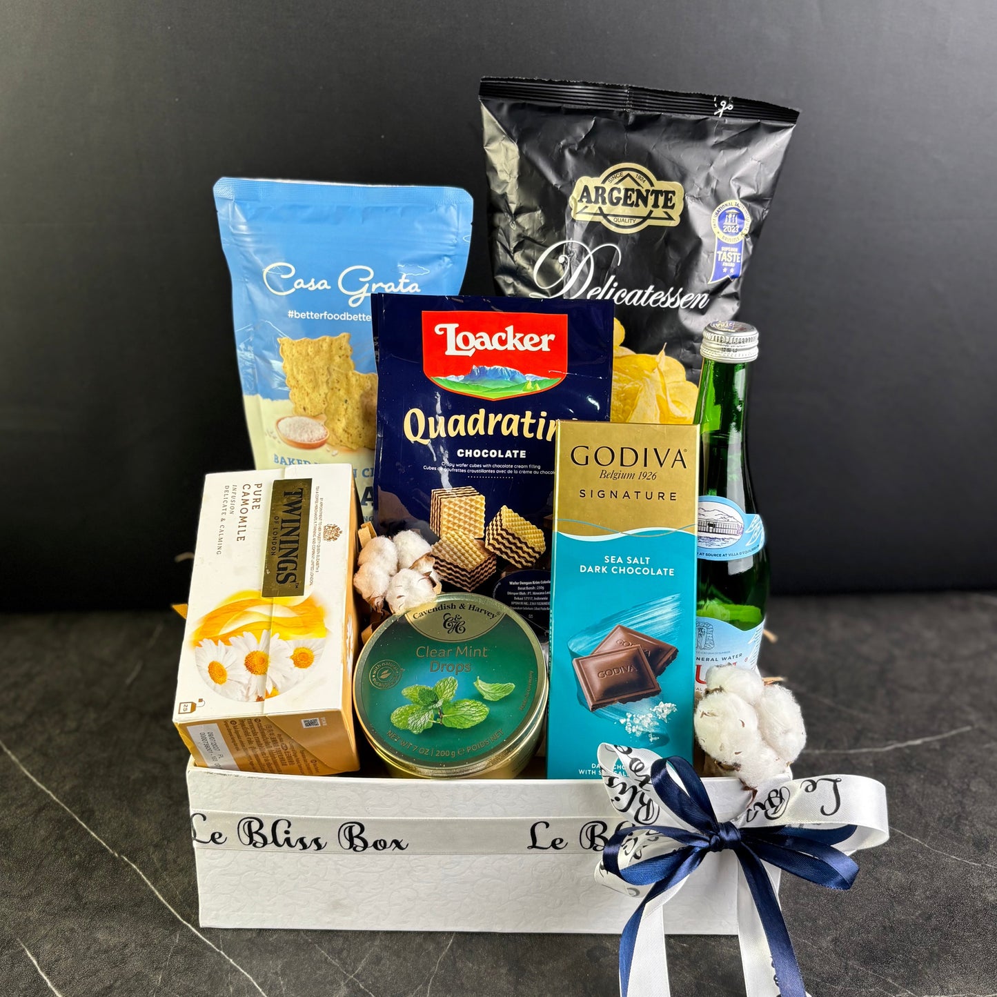 Gift basket with snacks and candies on a dark surface. Gourmet Hamper Jakarta