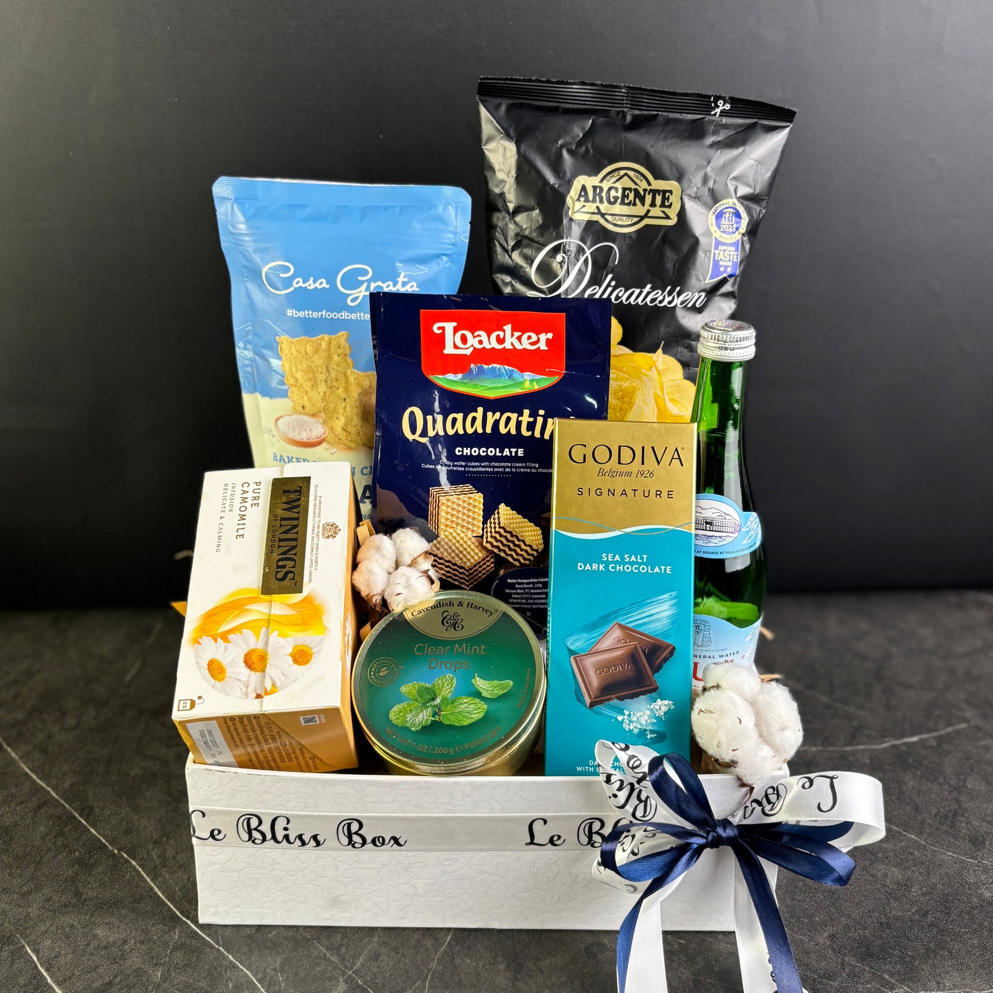 Gift basket with snacks and candies on a dark surface. Gourmet Hamper Jakarta