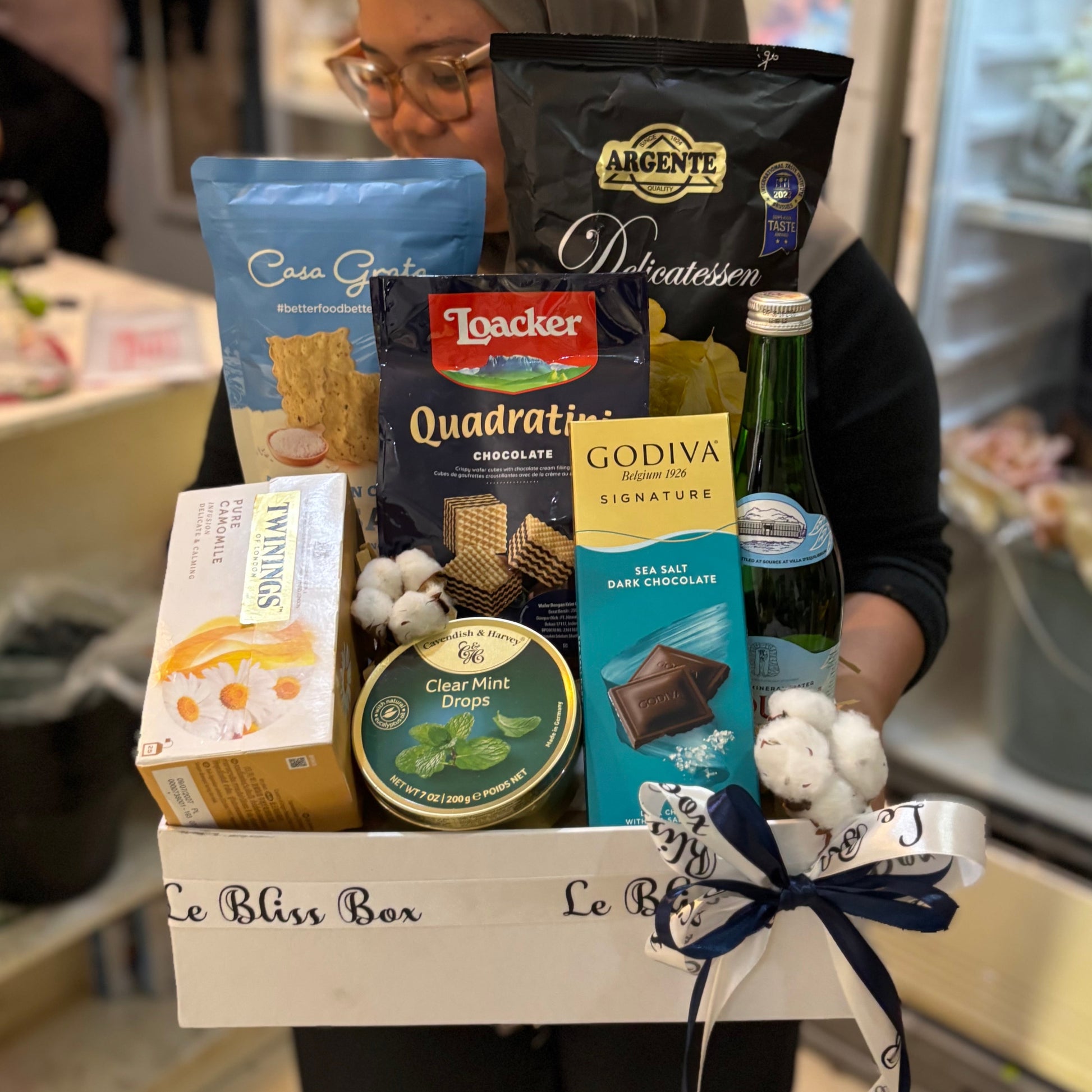 Gift basket with snacks and candies on a dark surface. Gourmet Hamper Jakarta by Le Bliss Box