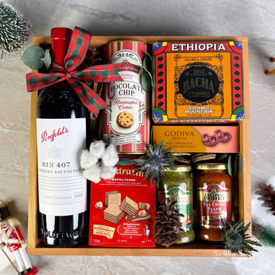 Gift basket with wine, cookies, coffee, and snacks on a textured surface. wine bin 407 penfolds, bacha coffee and other. gourmet hamper jakarta, surabaya. parcel natal jakarta, parcel natal surabaya