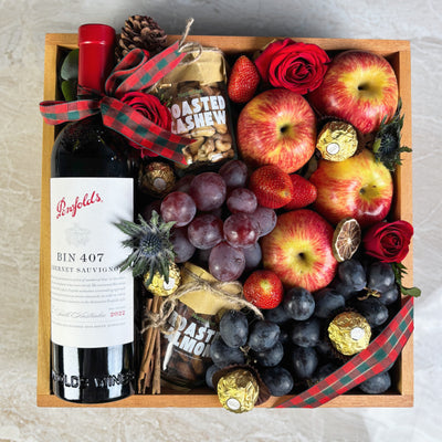 Gift box with wine, fruits, and chocolates on a light background. Gift box with Penfolds wine, fruits, and chocolates on a light background. Wine Hamper Jakarta by Le Bliss Box with roasted almond and cashew nuttanut. Penfolds Wine BIN 407 Hamper Jakarta
