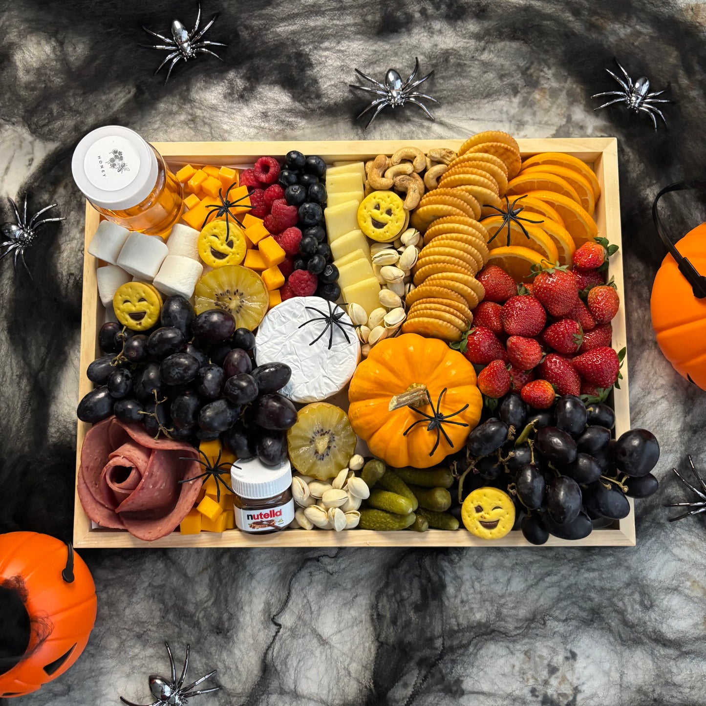 Halloween-themed charcuterie board with fruits, nuts, and candies on a dark background. halloween platter jakarta, halloween platter surabaya by le bliss platter