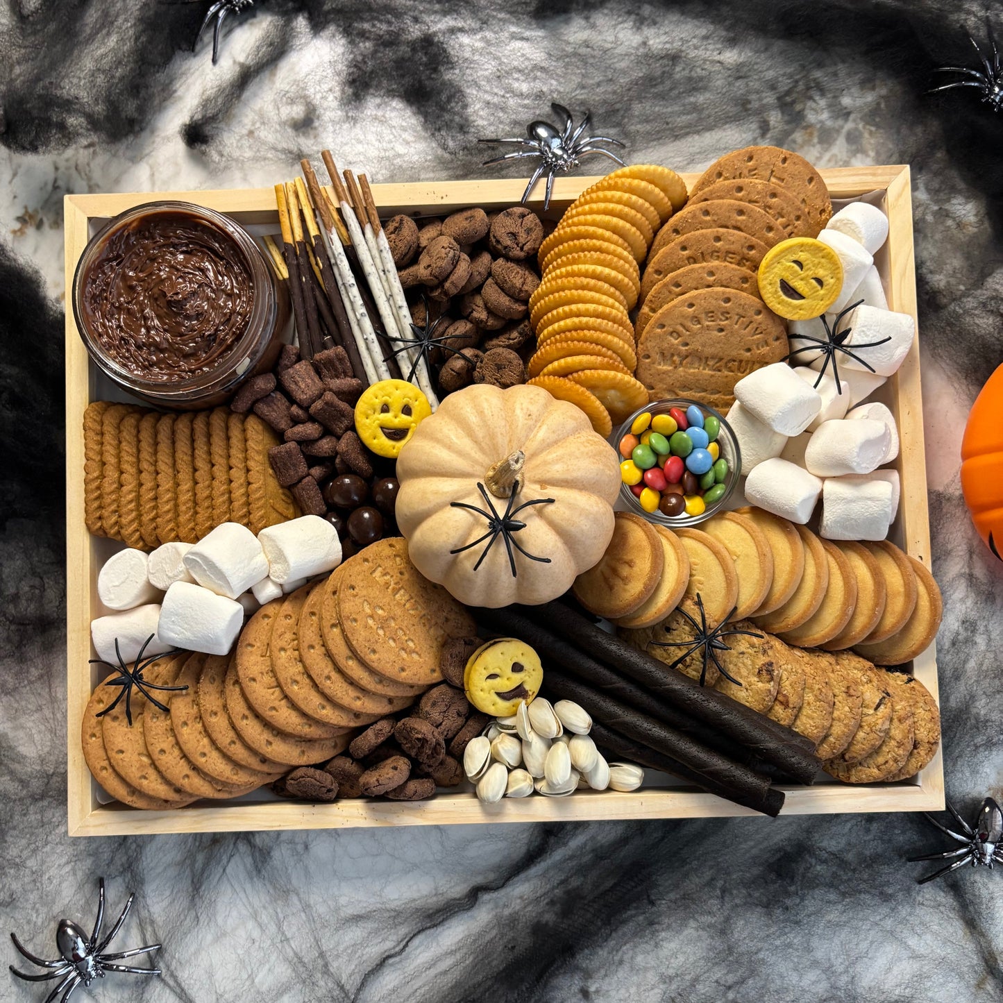 Halloween-themed snack platter with cookies, candies, and marshmallows on a marble surface. halloween sweet platter jakarta, halloween sweet platter surabaya by le bliss platter