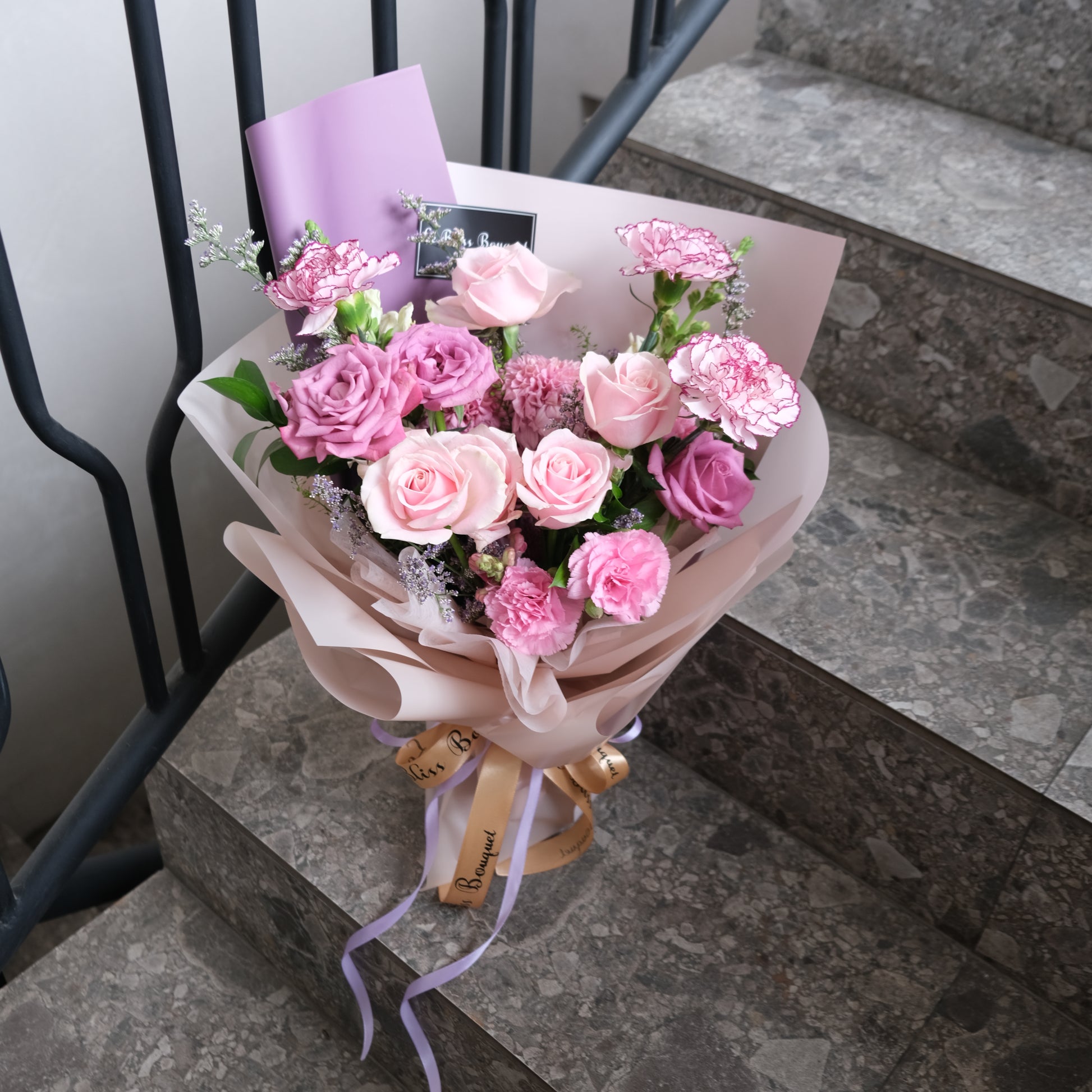 Mother's Day Bouquet of pink flowers with a card on a stone surface. Medium Bouquet dari Le Bliss Bouquet. Kado Hari Ibu yang elegan dengan mawar pink & lilac. Pengiriman Surabaya, Jakarta & Cirebon. Premium & heartfelt.