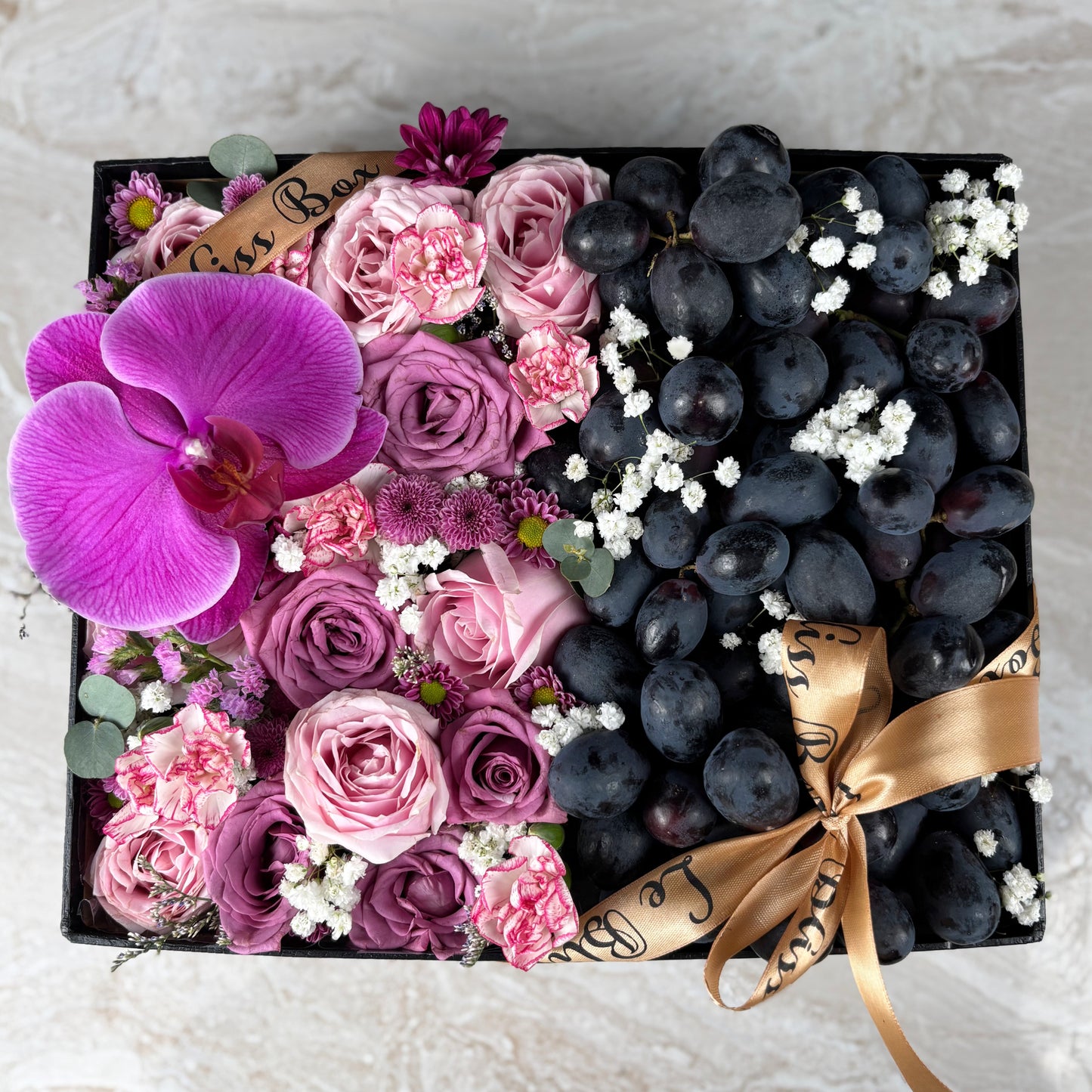 Pink Lilac Sonata Autumn Grape Box dari Le Bliss Bouquet. Kado Hari Ibu elegan dengan bunga & buah premium. Pengiriman Surabaya, Jakarta & Cirebon. Soft, sweet & luxurious. Kado Anggur  dan anggrek untuk Hari Ibu