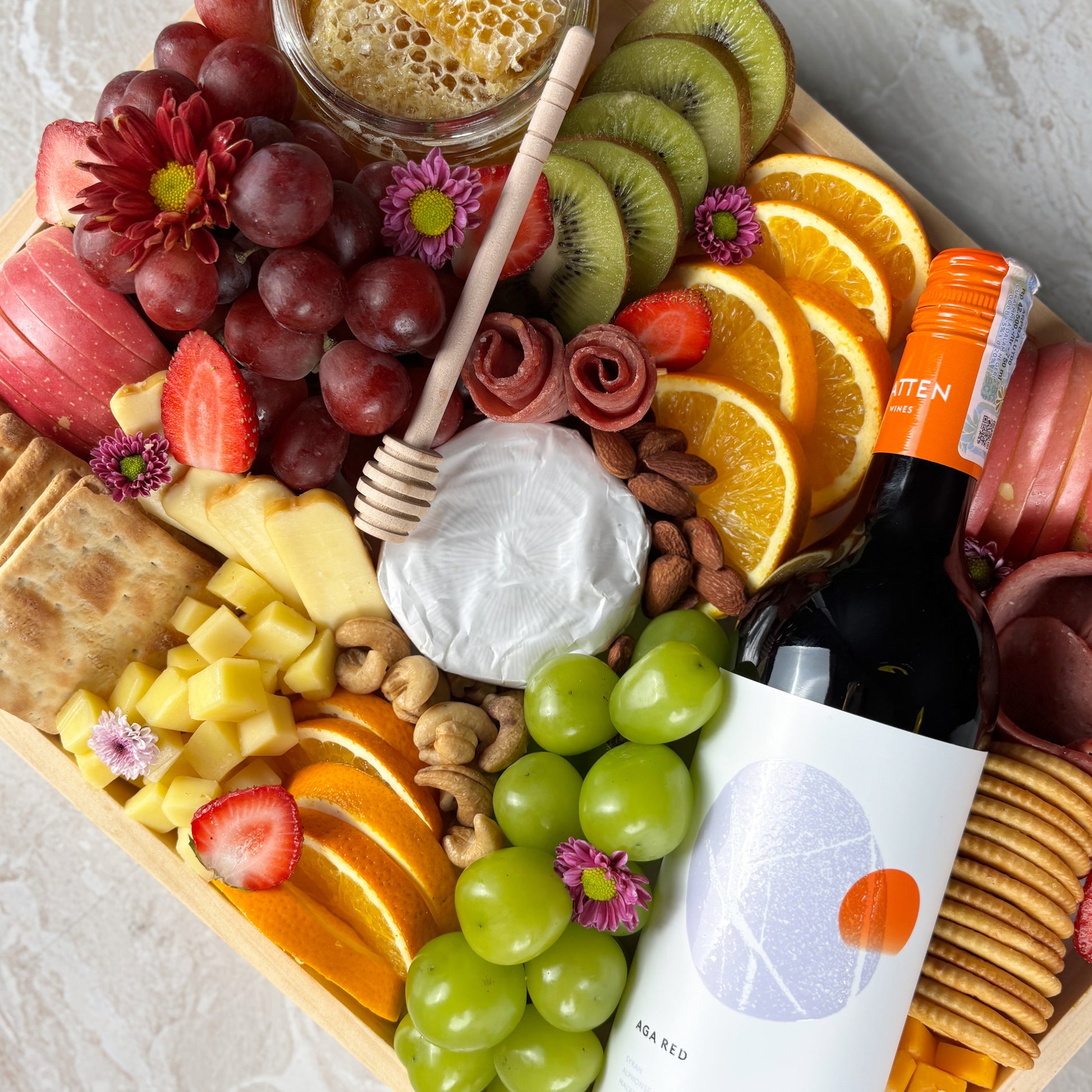 Red wine cheese platter on wooden tray with fruits and cheeses by le bliss platter. Luxury cheese platter gift with wine, grapes, and brie. best platter in jakarta, surabaya, cirebon