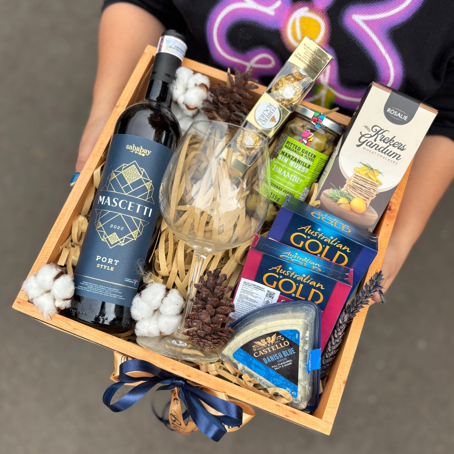 Wine Hamper Jakarta, Surabaya, Indonesia. Gift basket with wine, cheese, and other snacks on a dark surface. By Le Bliss Box