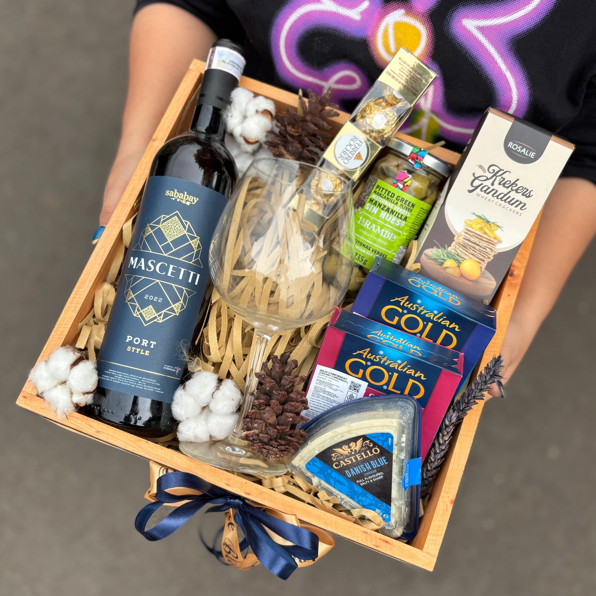 Wine Hamper Jakarta, Surabaya, Indonesia. Gift basket with wine, cheese, and other snacks on a dark surface. By Le Bliss Box