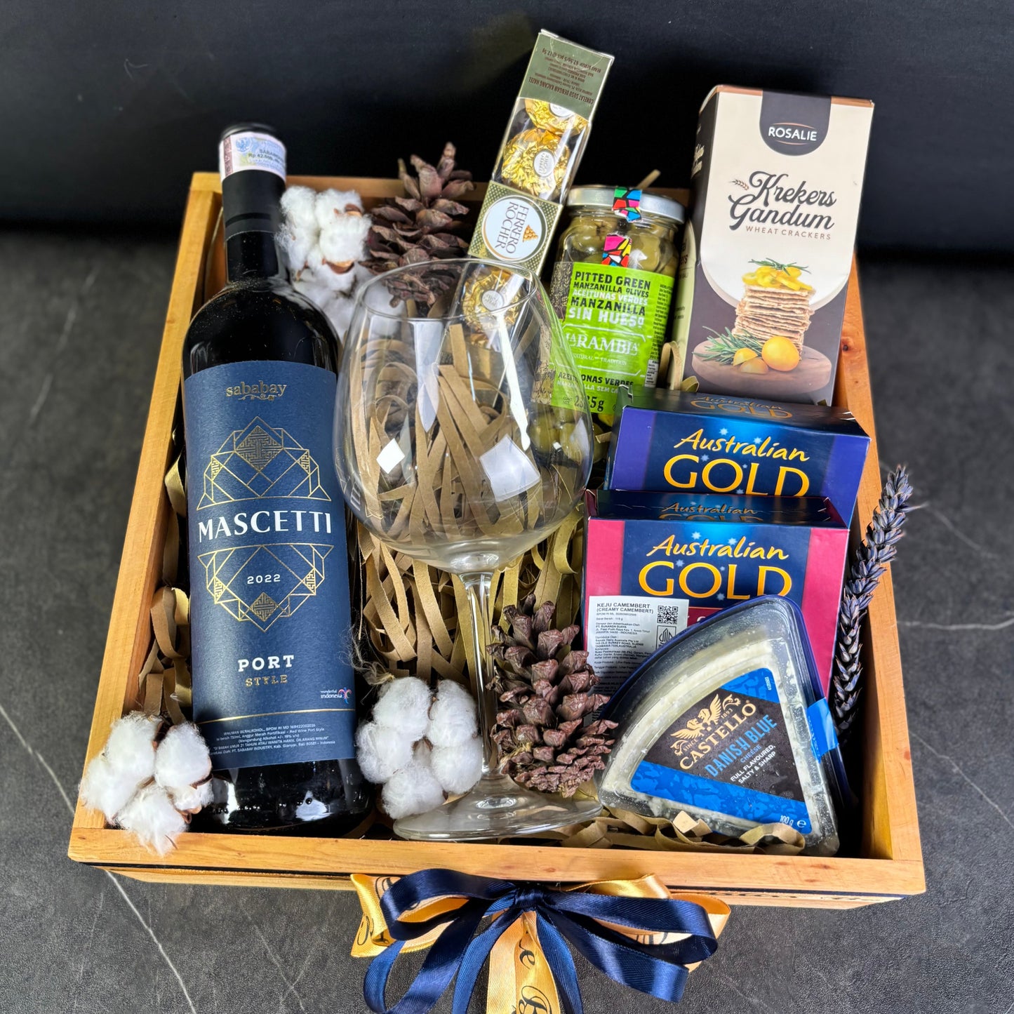 Wine Hamper Jakarta, Surabaya, Indonesia. Gift basket with wine, cheese, and other snacks on a dark surface
