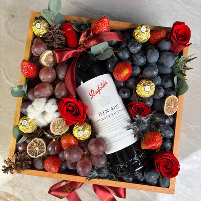 Wine bottle in a decorative box with fruits and flowers on a marble surface. Penfolds Wine Hamper Jakarta by Le Bliss Box